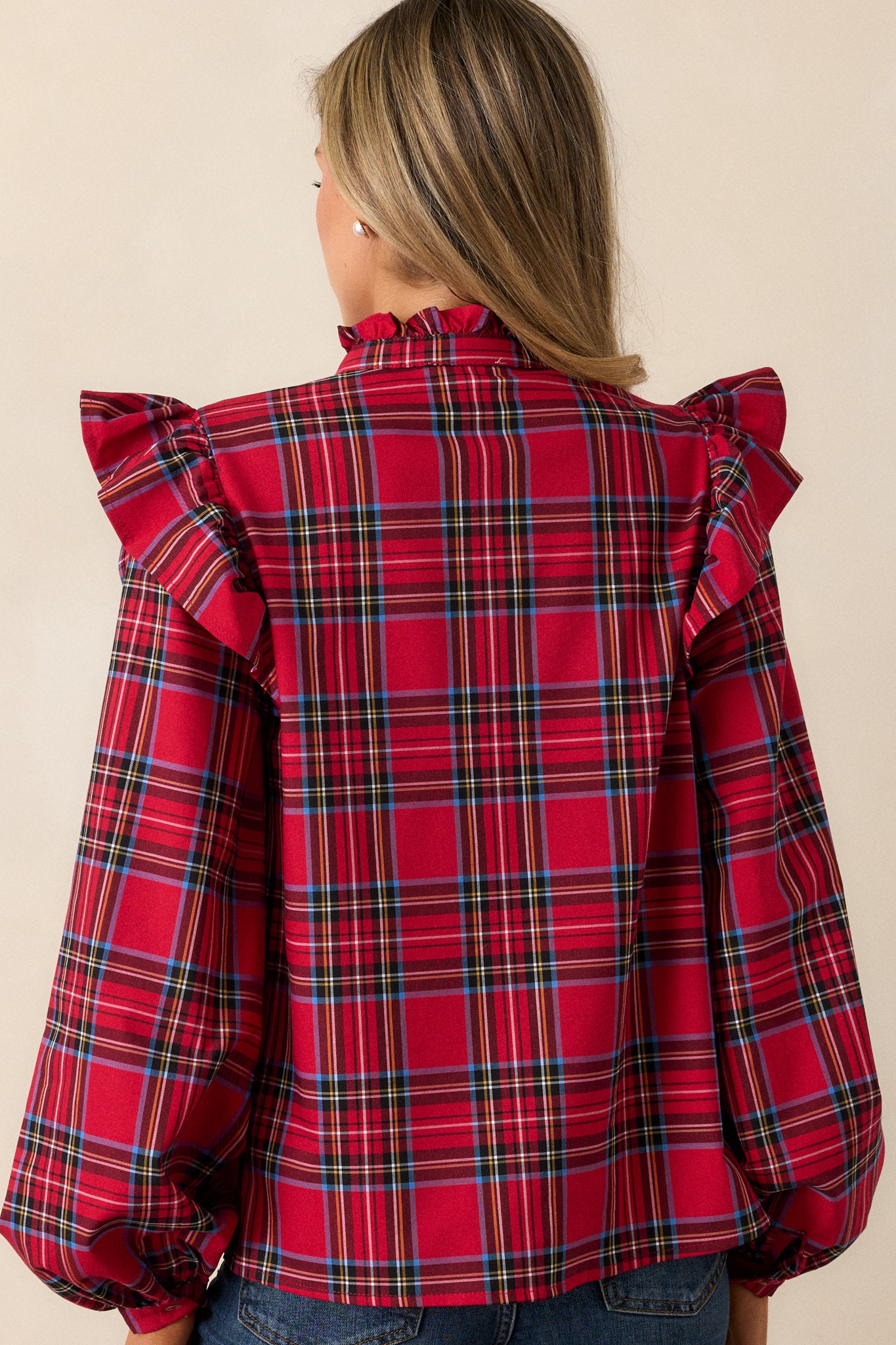 Close view of the back of the top, displaying the ruffle neckline and the flow of the fabric down to the buttoned cuffs.