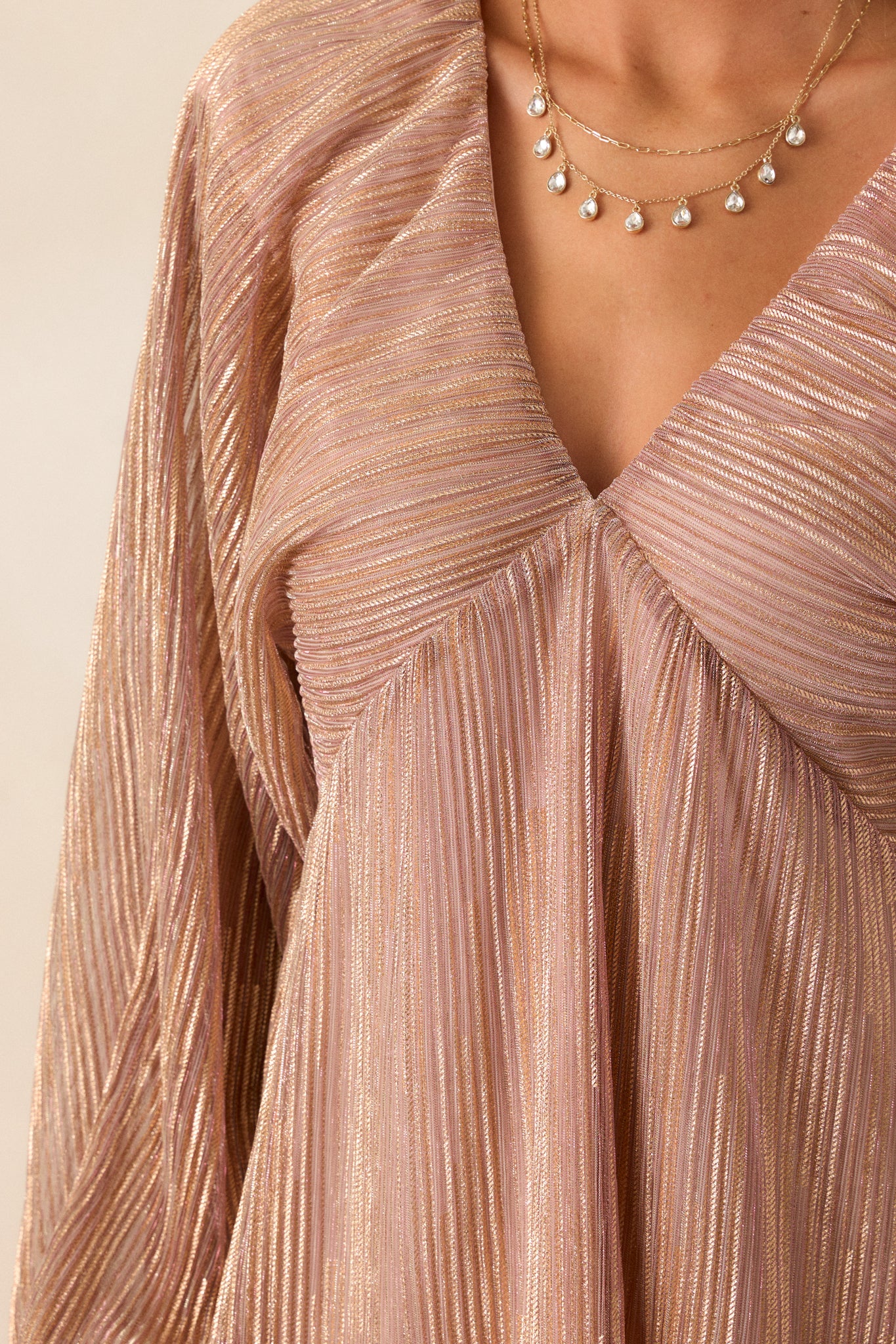 Close-up of the fabric texture, highlighting the sheen of the rose gold material and the stitching around the v-neck neckline.