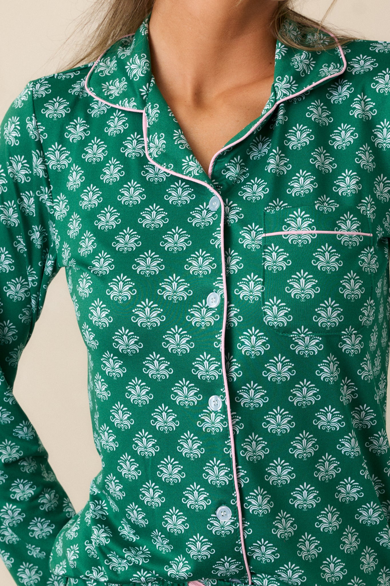 Close-up of the Fleur de Lis pattern and pink trim on green pajama top, highlighting the fabric texture.