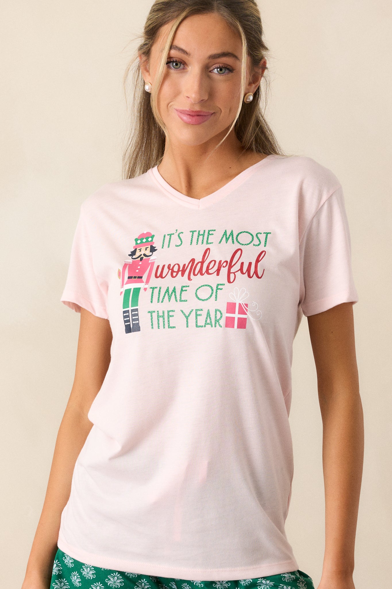 Front view of the top that captures its light pink hue, relaxed silhouette, and playful holiday-themed design.