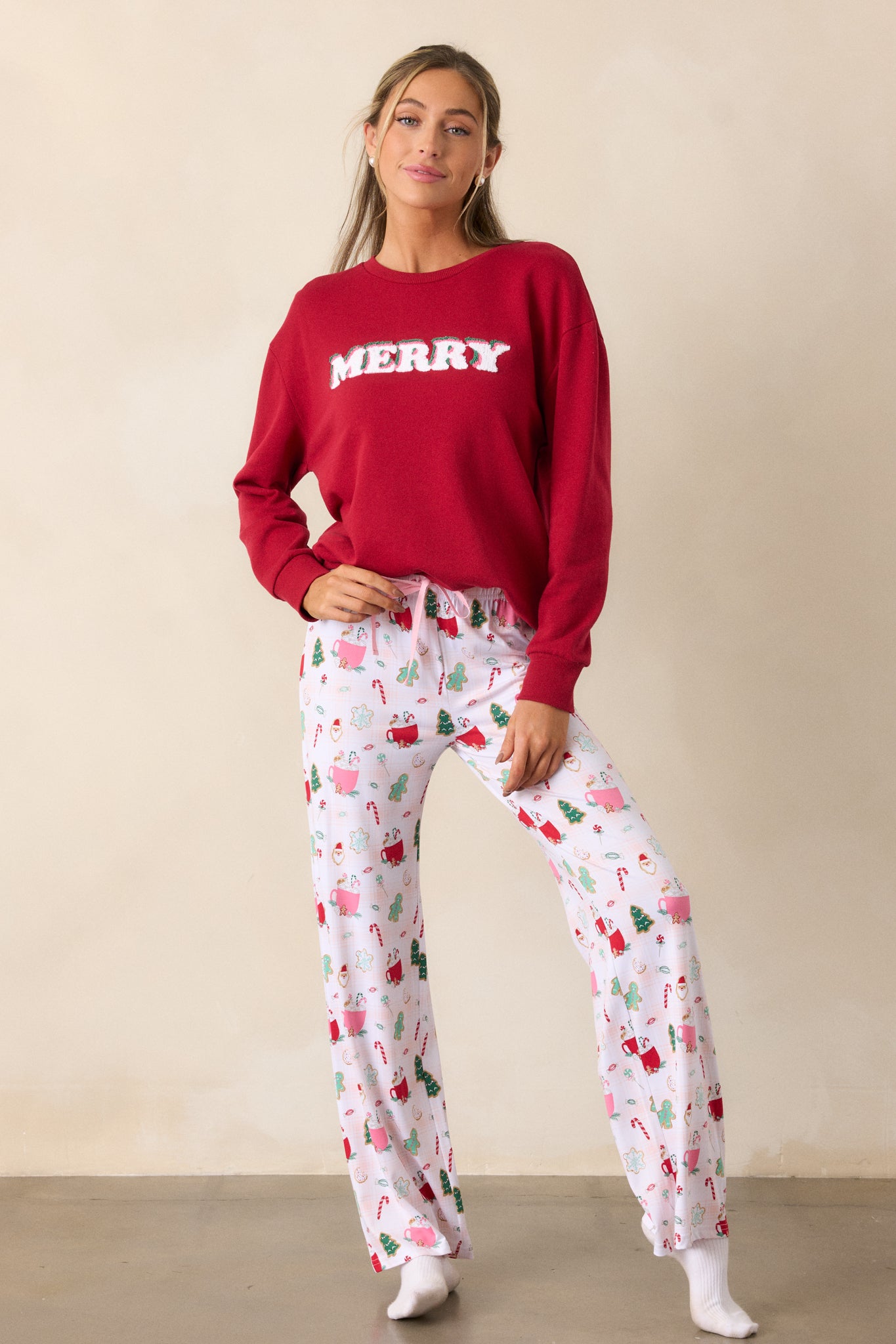 Full view of the red sweatshirt displaying a relaxed fit, featuring long sleeves with ribbed hems and the word "Merry" prominently across the front.