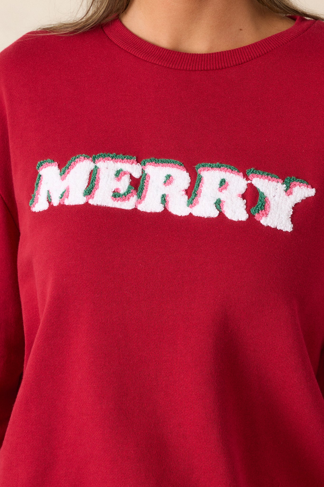 Close-up shot of the "Merry" detailing on the front, capturing the font style and placement against the vibrant red fabric.