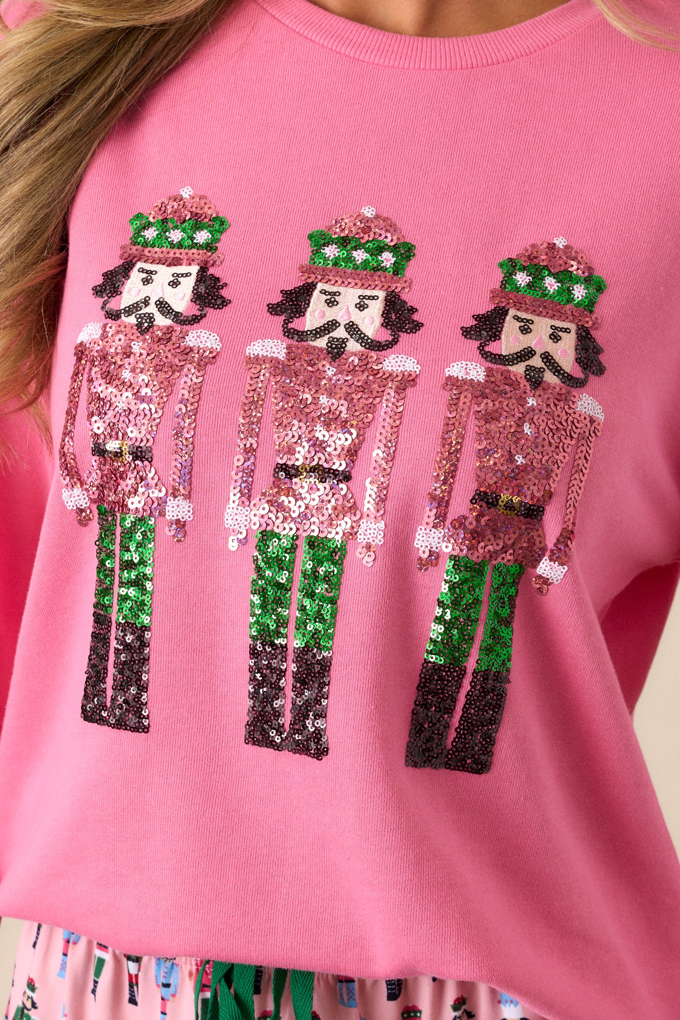 Close up of the nutcracker sequin design of this pink, long sleeve sweatshirt.