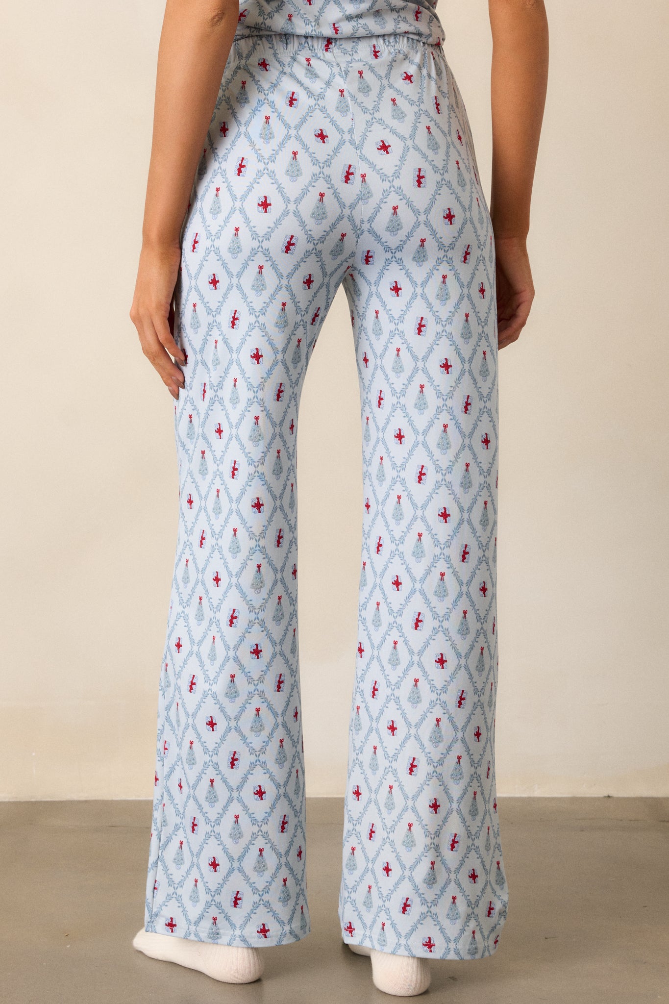 View of the back of the pajama pants, featuring the relaxed fit, continuous tree and present print, and the waistband from behind.