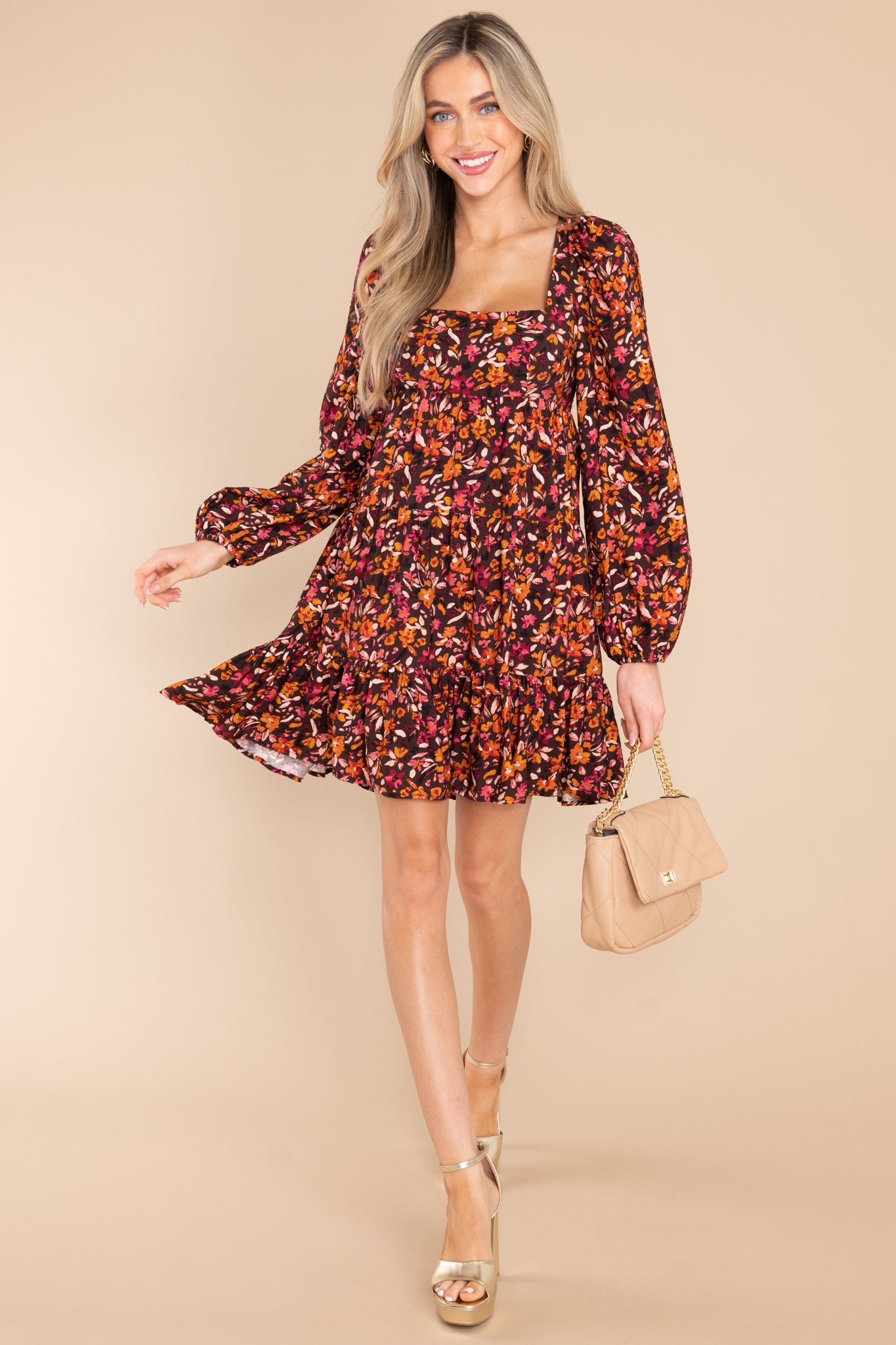 Full body view of this dress that features a square neckline, a self tie at the back of the neck, a smocked insert on the back, flowy sleeves with elastic cuffs, and a tiered skirt.