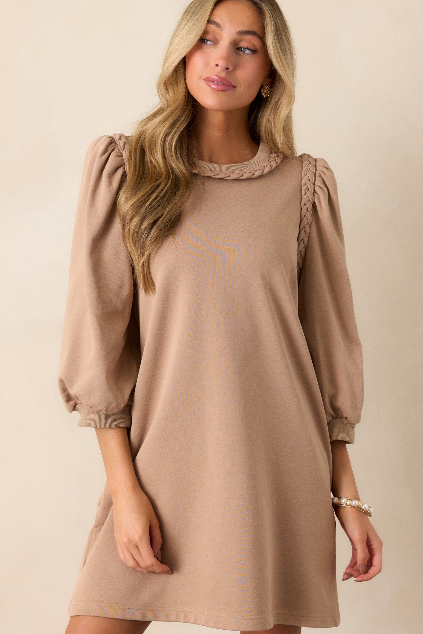 Front view of a tan dress featuring a braided neckline, braided shoulder detailing, puff 3/4 sleeves and a boxy fit.