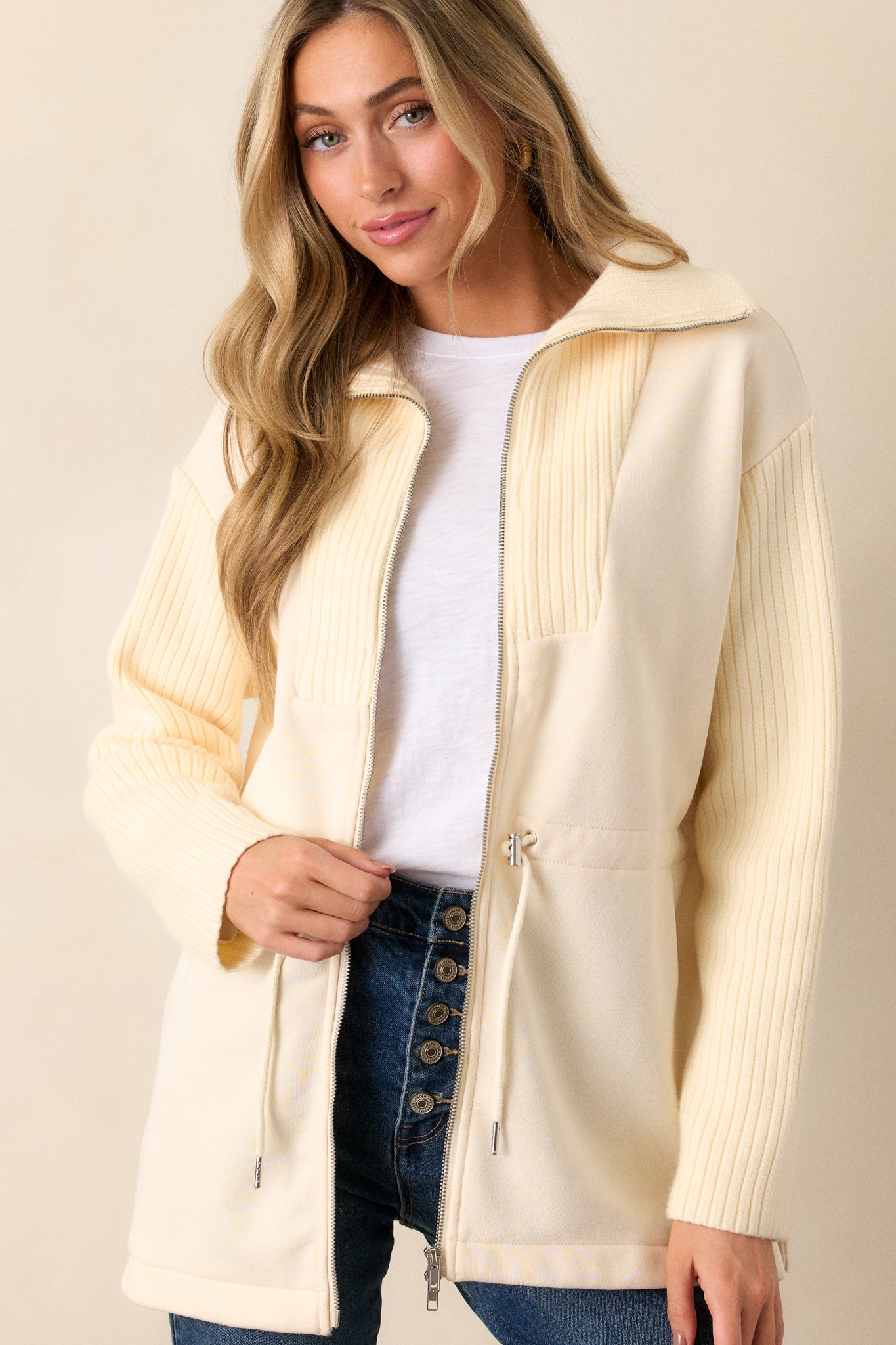 A cropped view of the upper portion of the jacket, focusing on the knit high neck, contrasting fabrics, and the zipper closure.