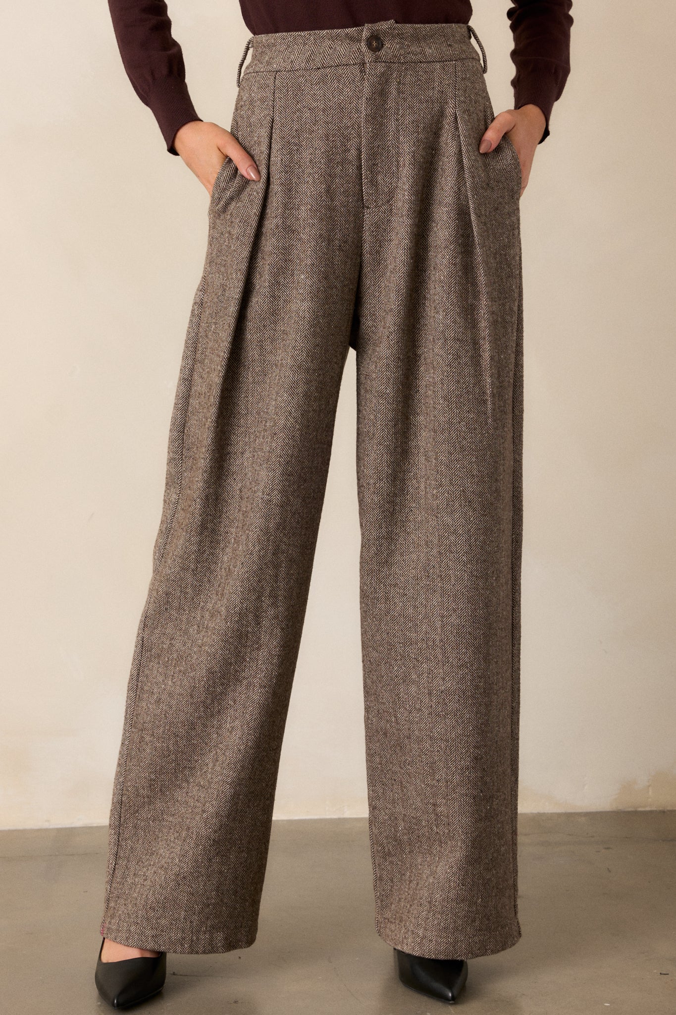 Close-up of the waistband and upper portion of the brown herringbone pants, emphasizing the functional belt loops and concealed zipper closure.