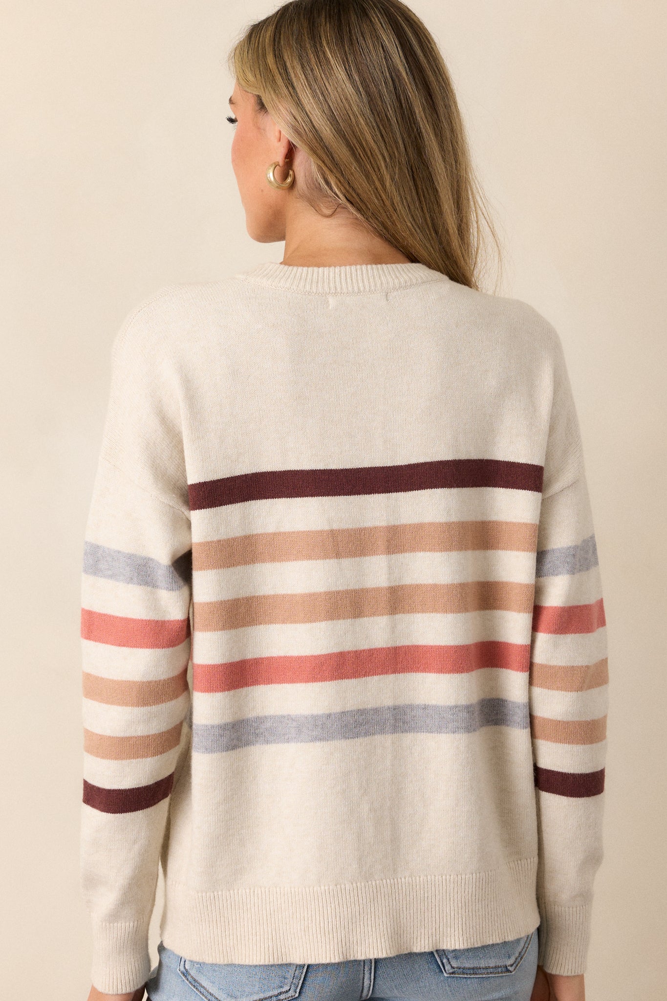 Rear view of the beige stripe sweater, focusing on the horizontal stripe pattern across the back and the ribbed details at the collar and hem.