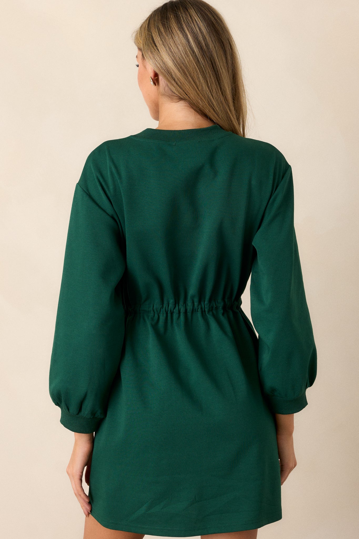 A back view of the green dress, emphasizing the long sleeves and the overall design of the dress, including the ribbed neckline.