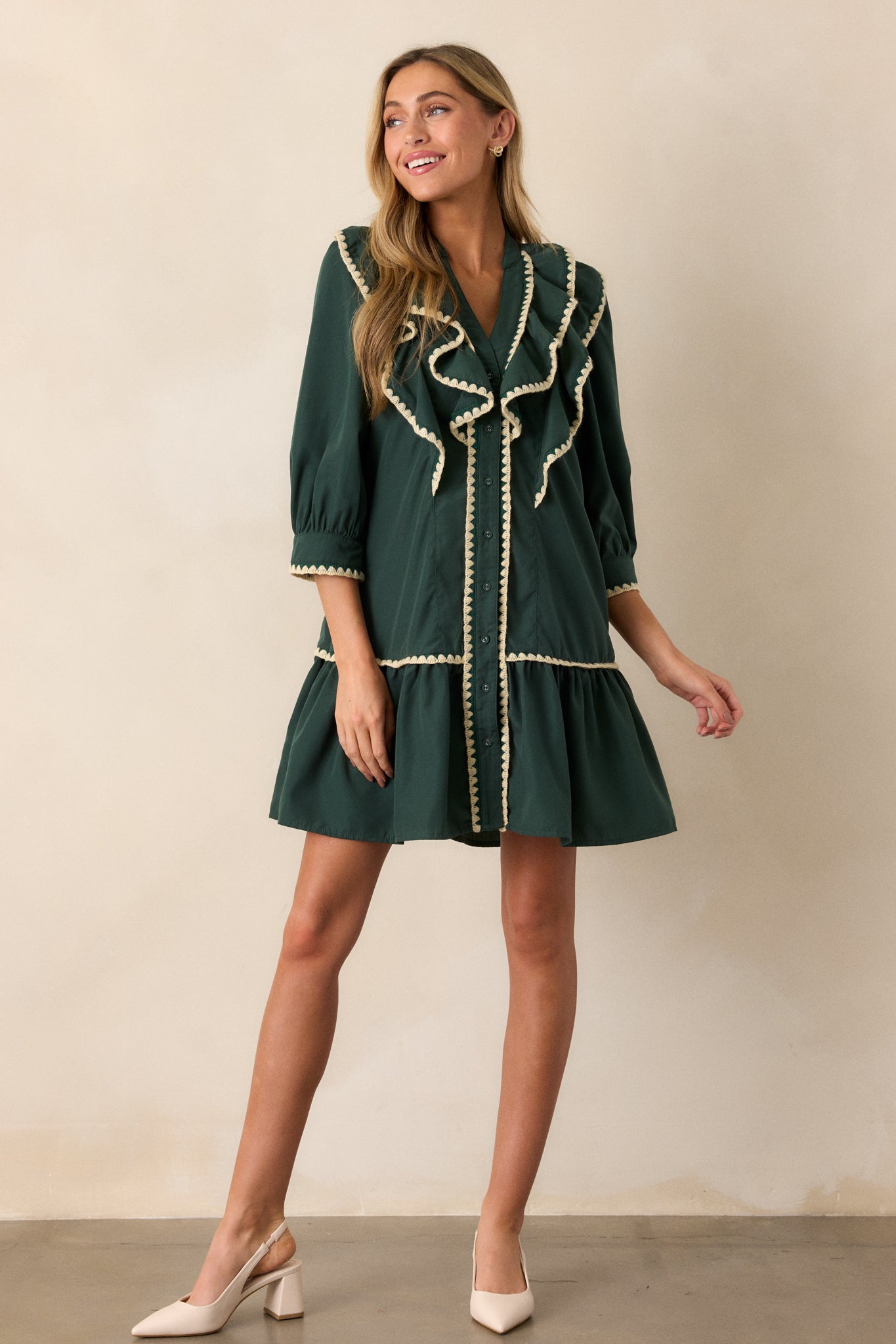 A front-facing view of the green dress, highlighting the 3/4 length sleeves with cream-trimmed cuffs and the tiered skirt design.