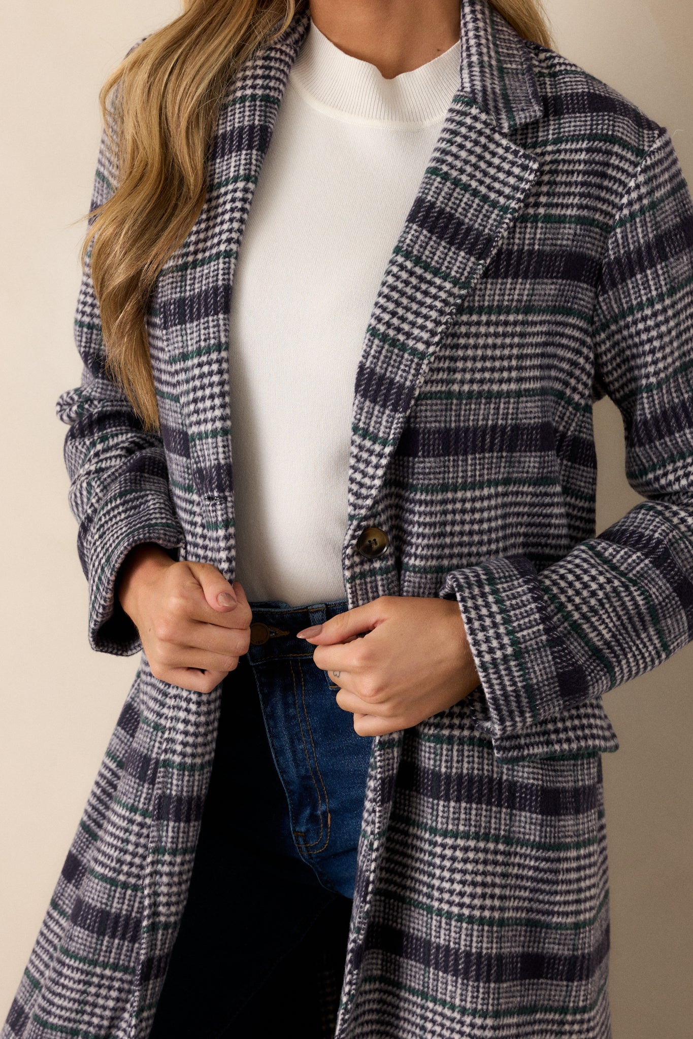 A close-up of the functional buttons on the front of the navy plaid coat, highlighting the pattern and button details.