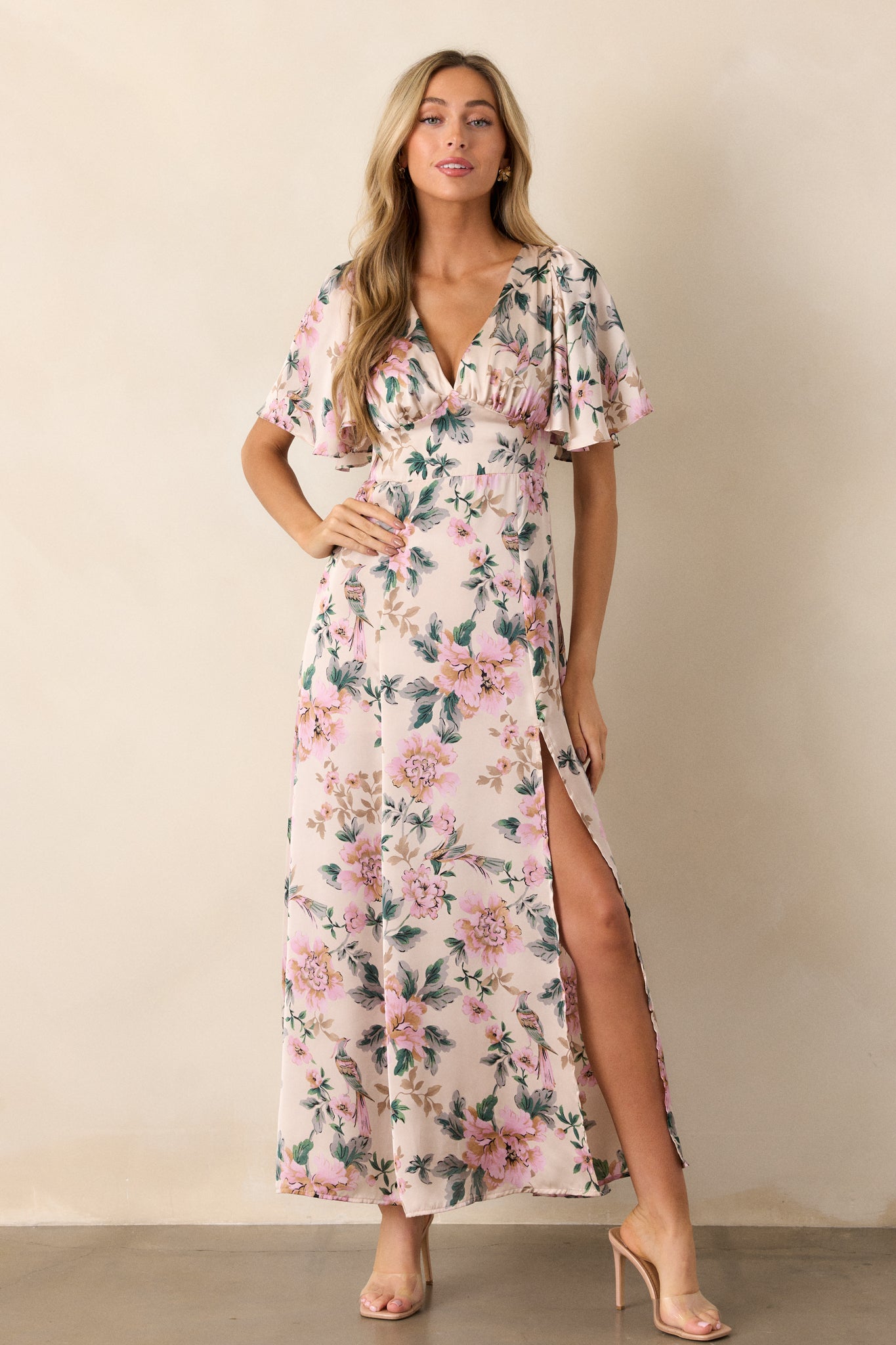 A full view of the ivory floral maxi dress, featuring a deep V-neckline and flutter sleeves, showcasing the vibrant floral print and fitted waist that creates an elegant silhouette.