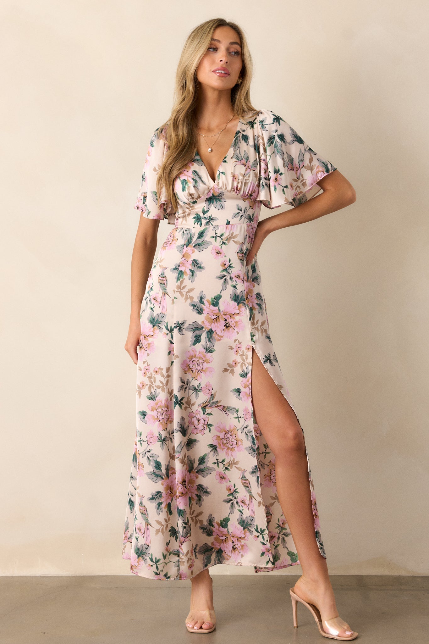 A front view of the dress emphasizing the intricate floral pattern, with the deep V-neckline and flutter sleeves framed by the vibrant blooms.