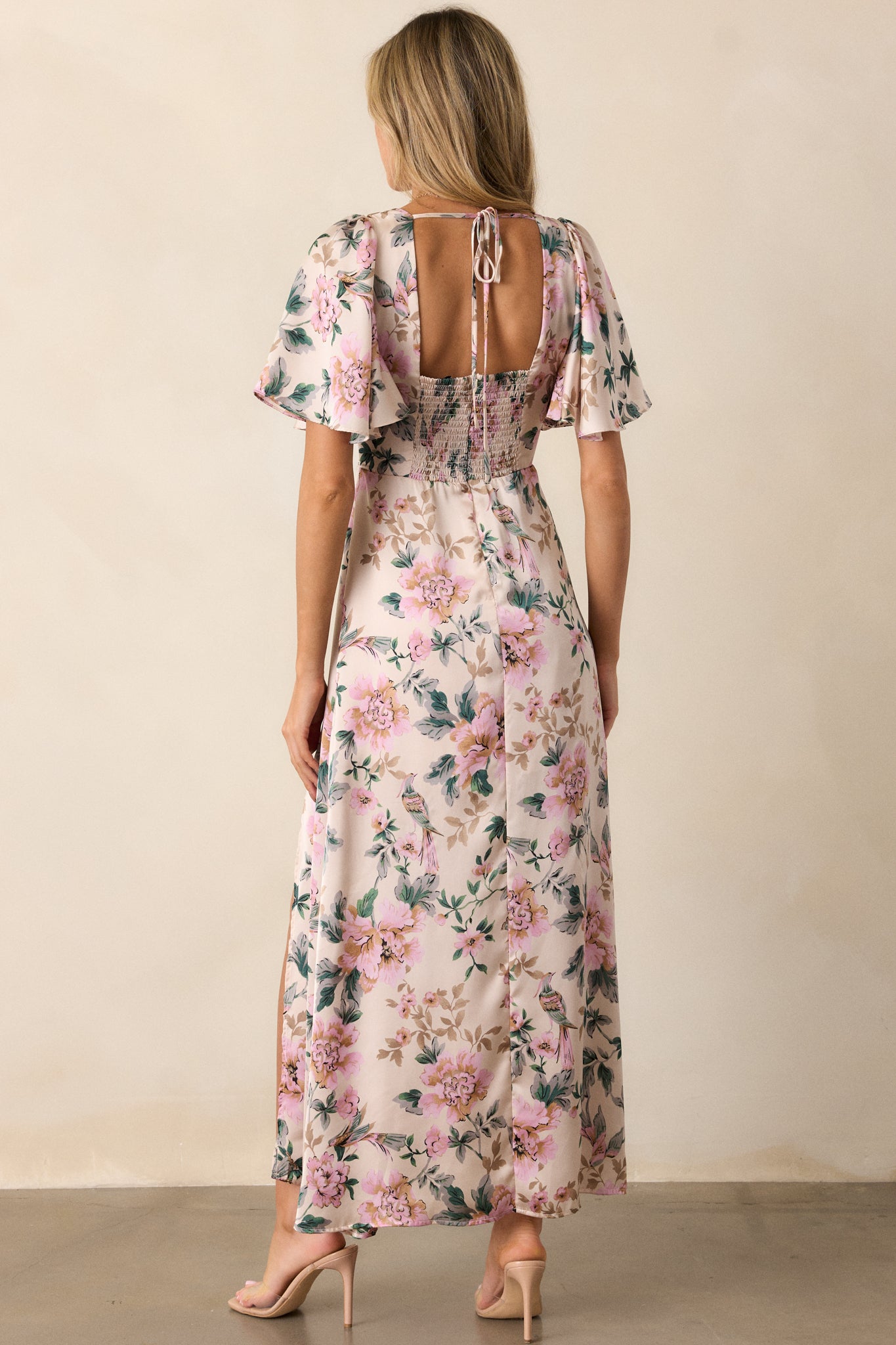 A view from the back of the dress, showcasing the deep V-neckline and how the flutter sleeves fall gracefully, complementing the overall design and floral pattern.