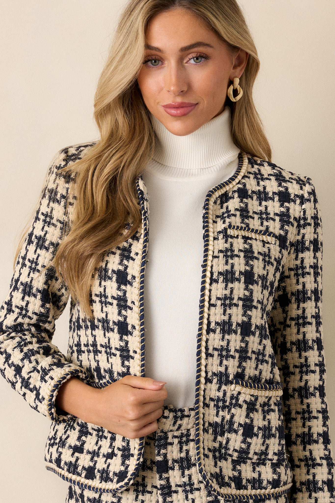 A navy tweed jacket with a houndstooth design, boxy fit, functional front pockets, and double gold rope twist trim along the edges.