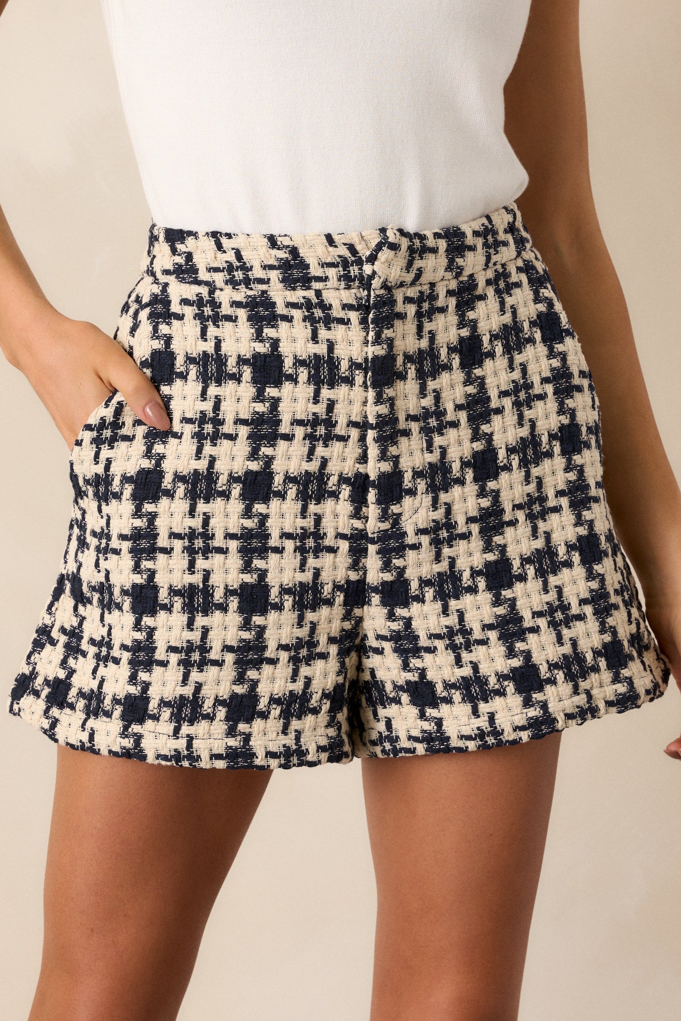 A close-up view of one of the functional hip pockets on the navy shorts, emphasizing the houndstooth design and the stitching details.