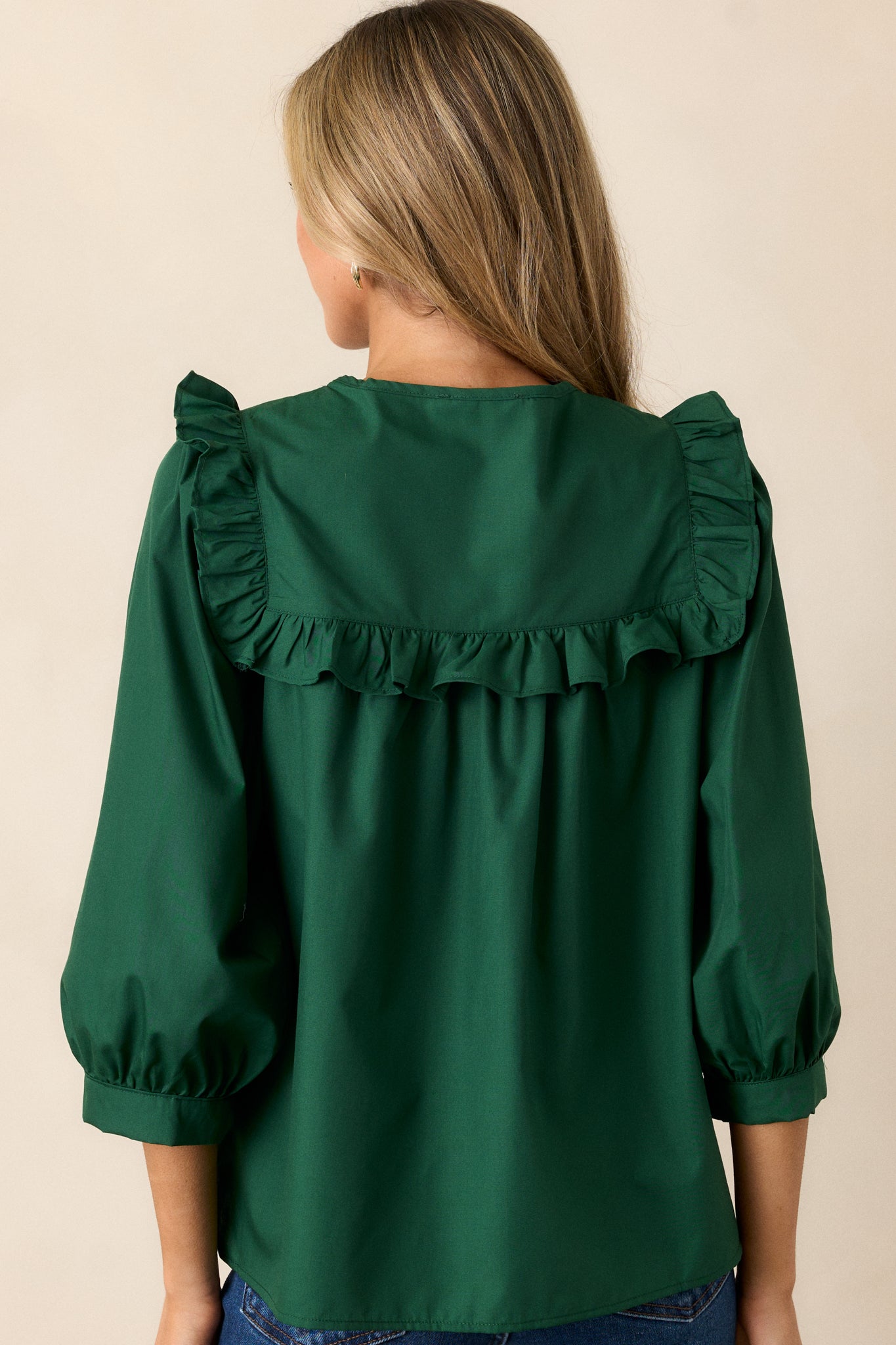 The back view of the hunter green top, highlighting the simple yet elegant design while showcasing the relaxed fit of the fabric.