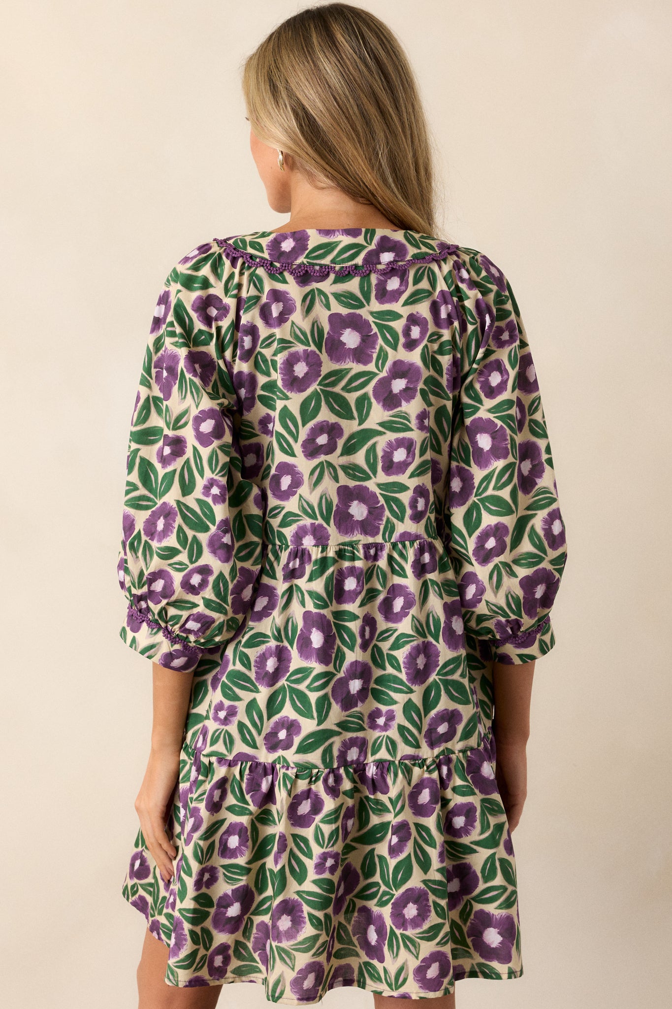 View of the back of the dress, featuring the continuous floral pattern, the tiered design, and the scalloped detailing along the hem.