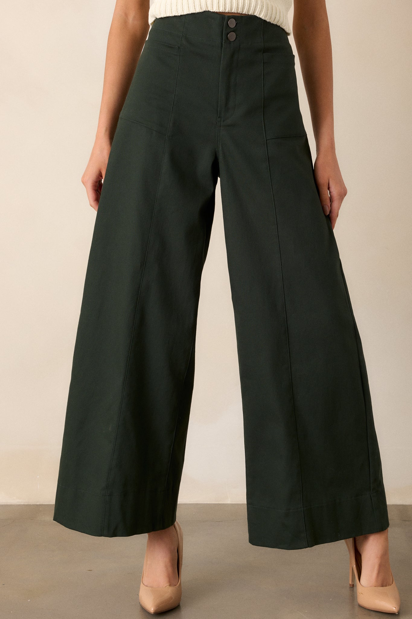 A cropped view of the pants focusing on the button and zipper closure, detailing the sleek design that complements the high waist.