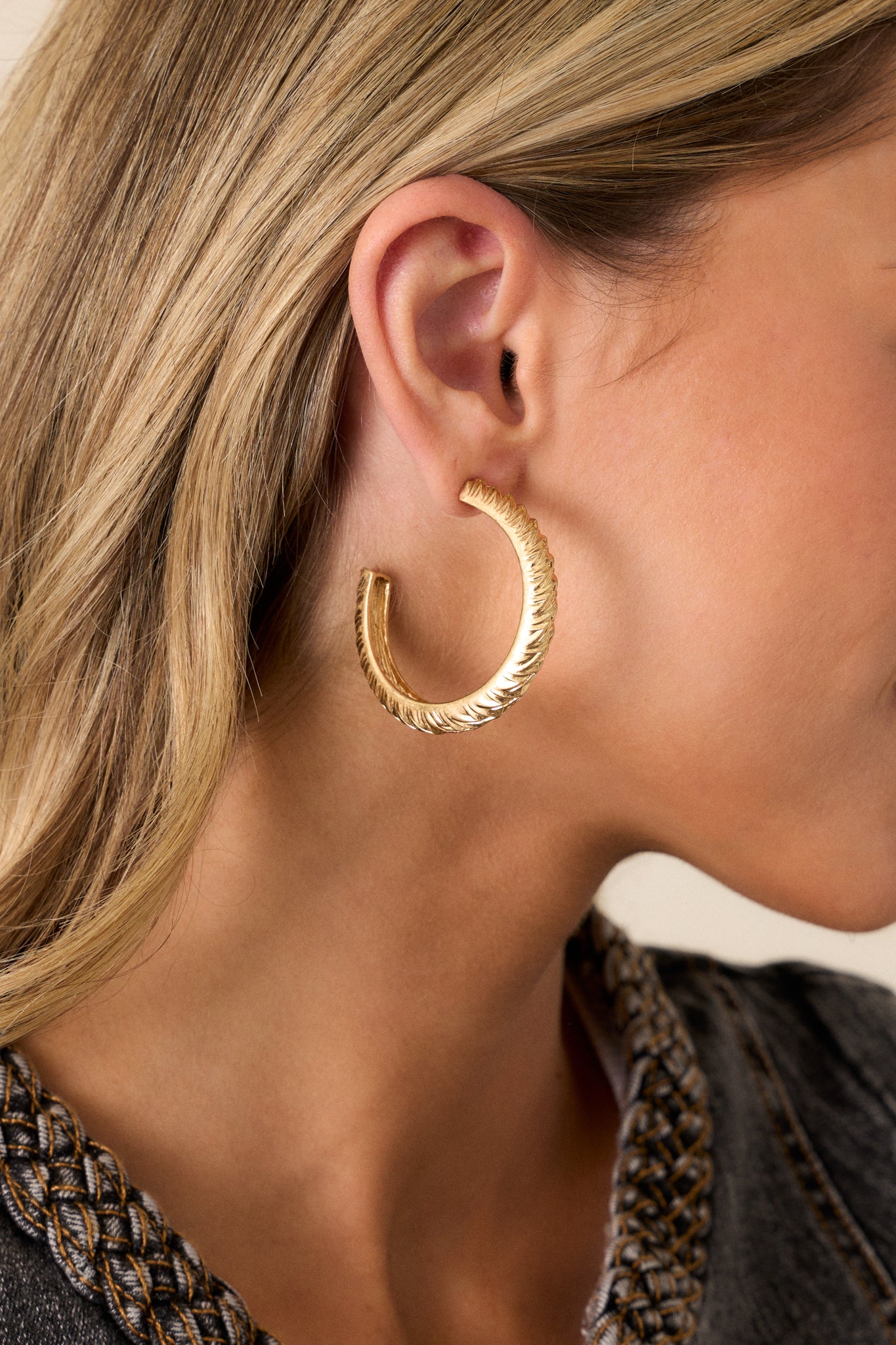 These gold hoop earrings feature a gold finish, a grooved textured design, and secure post backings.