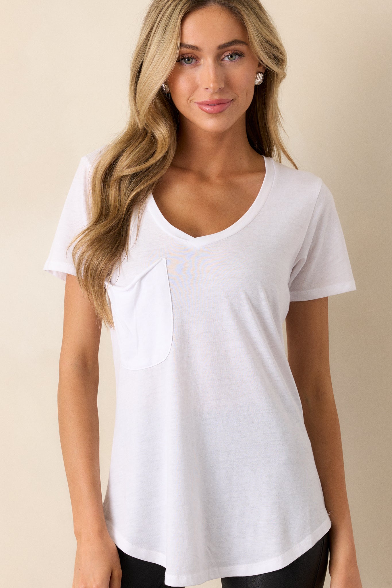 Front view of a white tee featuring a v-neckline, a functional chest pocket, a super soft fabric, and a scooped hemline.