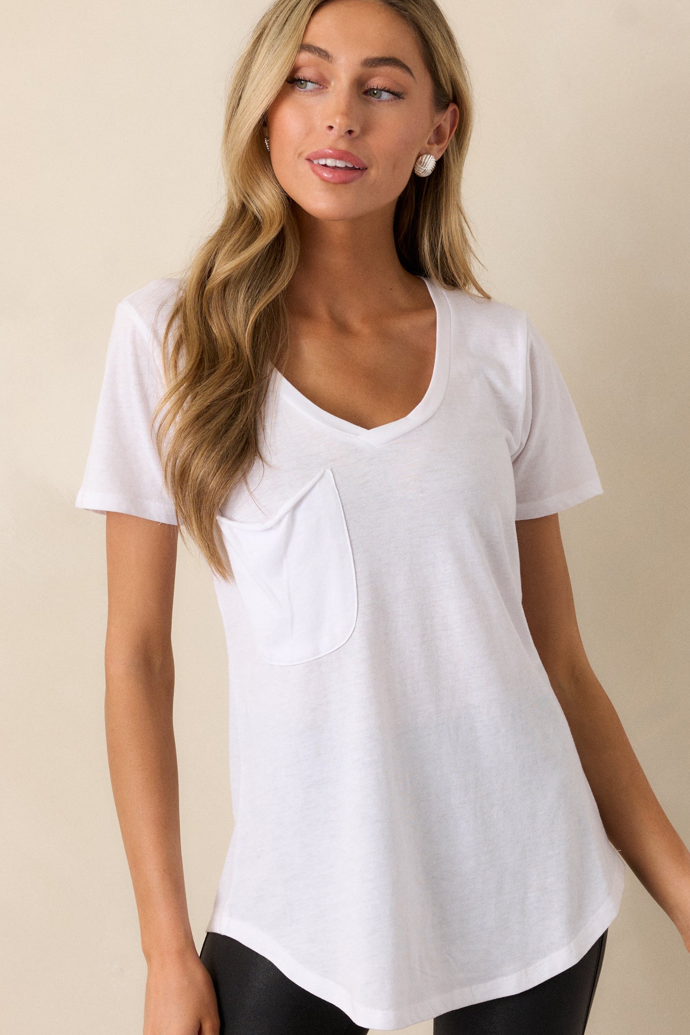 Front angled view of a white tee featuring a v-neckline, a functional chest pocket, super soft fabric, and a scooped hemline