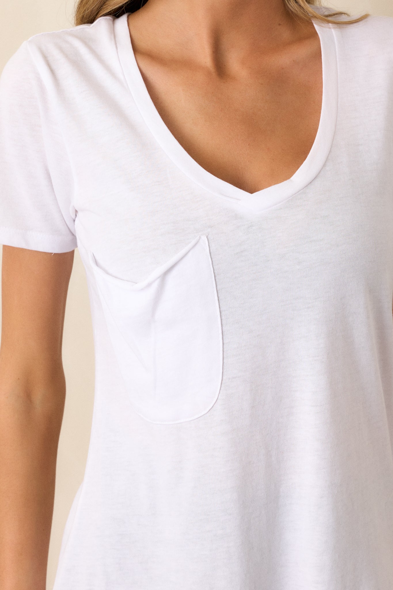 Close-up of the white tee showing the v-neckline, functional chest pocket, and the texture of the super soft fabric.