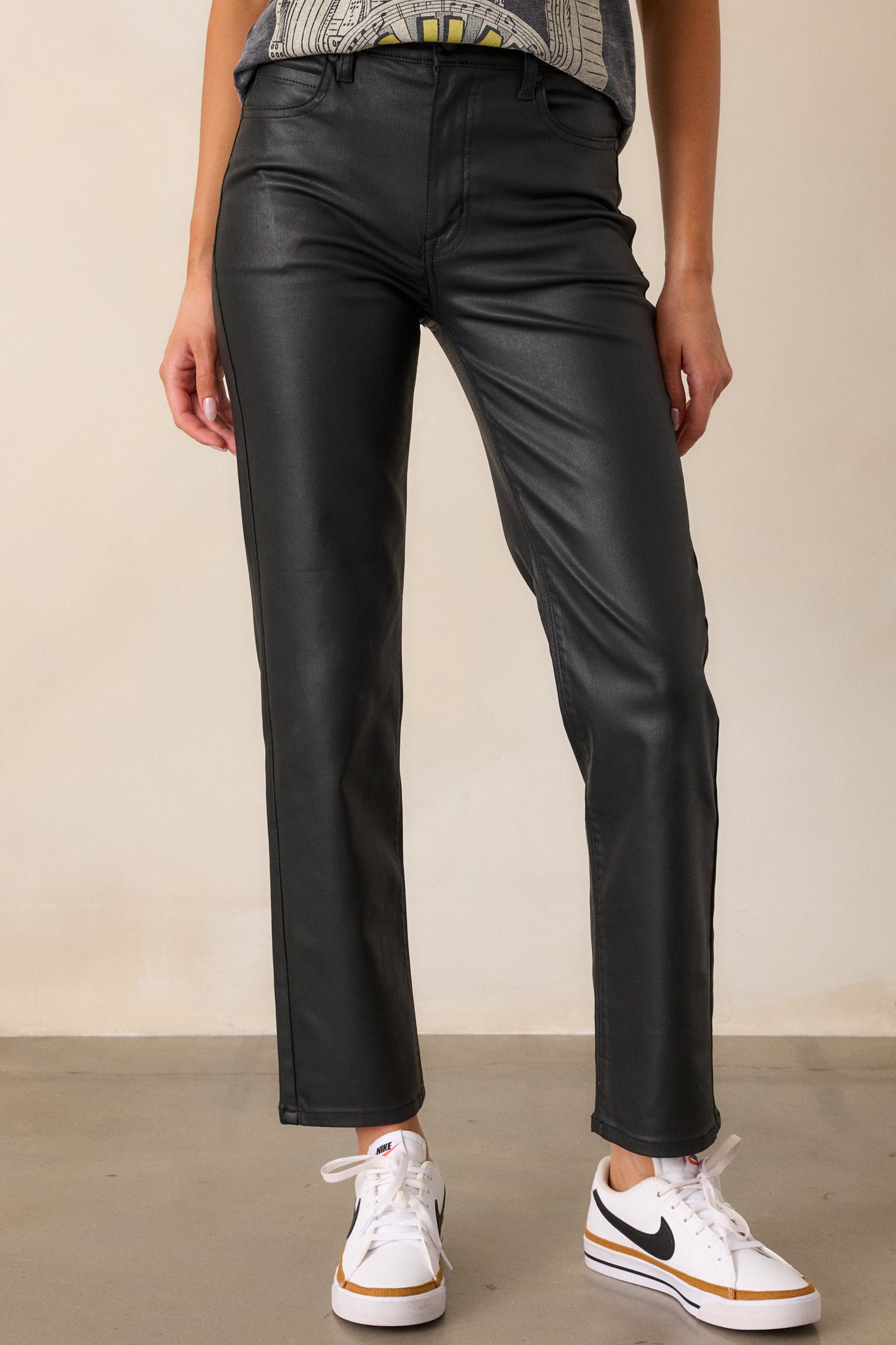 Front angle of the black faux leather pants highlighting the sleek fit, straight leg design, and high-waisted cut.