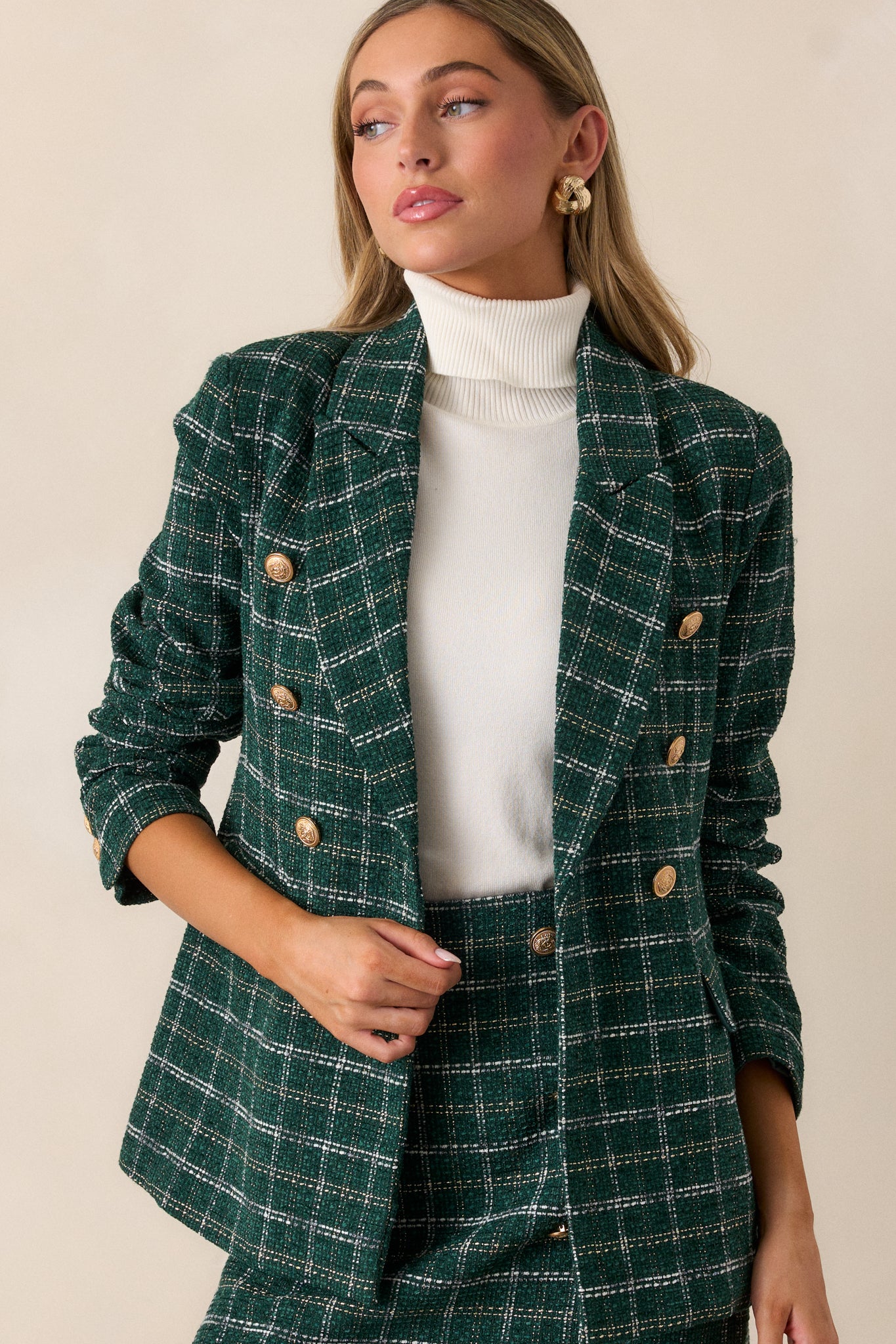 Front view of the coat, showcasing the intricate gold and white stitching throughout the tweed fabric and the functional hip pockets.