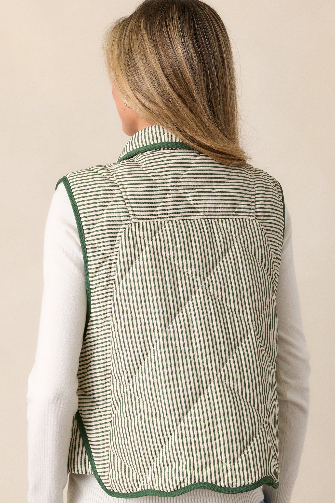 Back view of the green vest, showing the quilted stripe pattern throughout and green knit hems along the sides and wavy bottom seam.