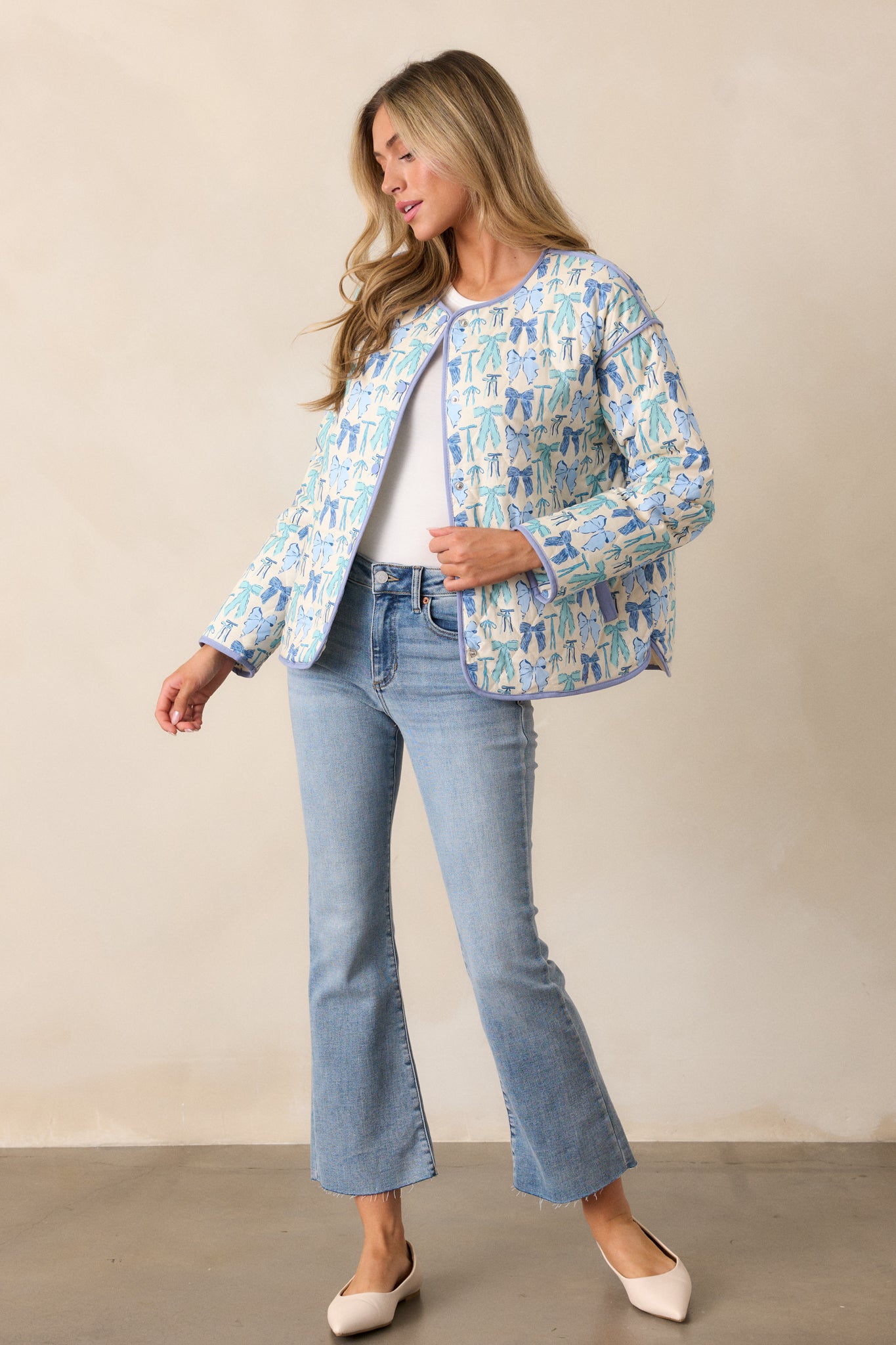 Side angle of the jacket, emphasizing the blue trim along the edges and showcasing one of the functional hip pockets with a visible bow pattern.