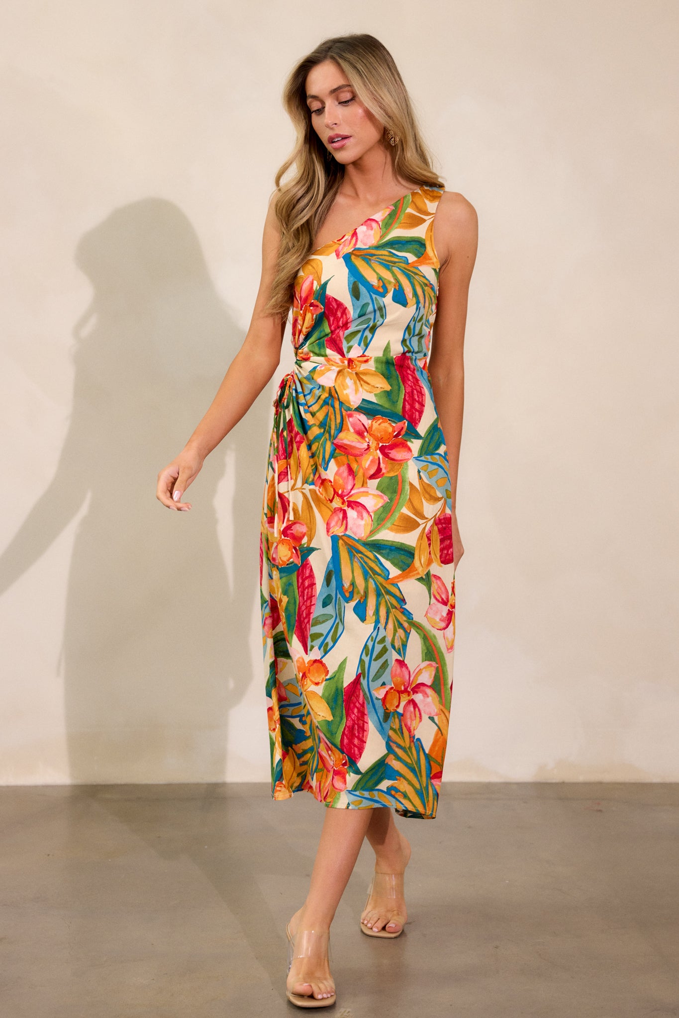 Front view of the multi-print dress, highlighting the asymmetric neckline, one-shoulder style, and the flowing skirt with a self-tie cut-out detail on the side.