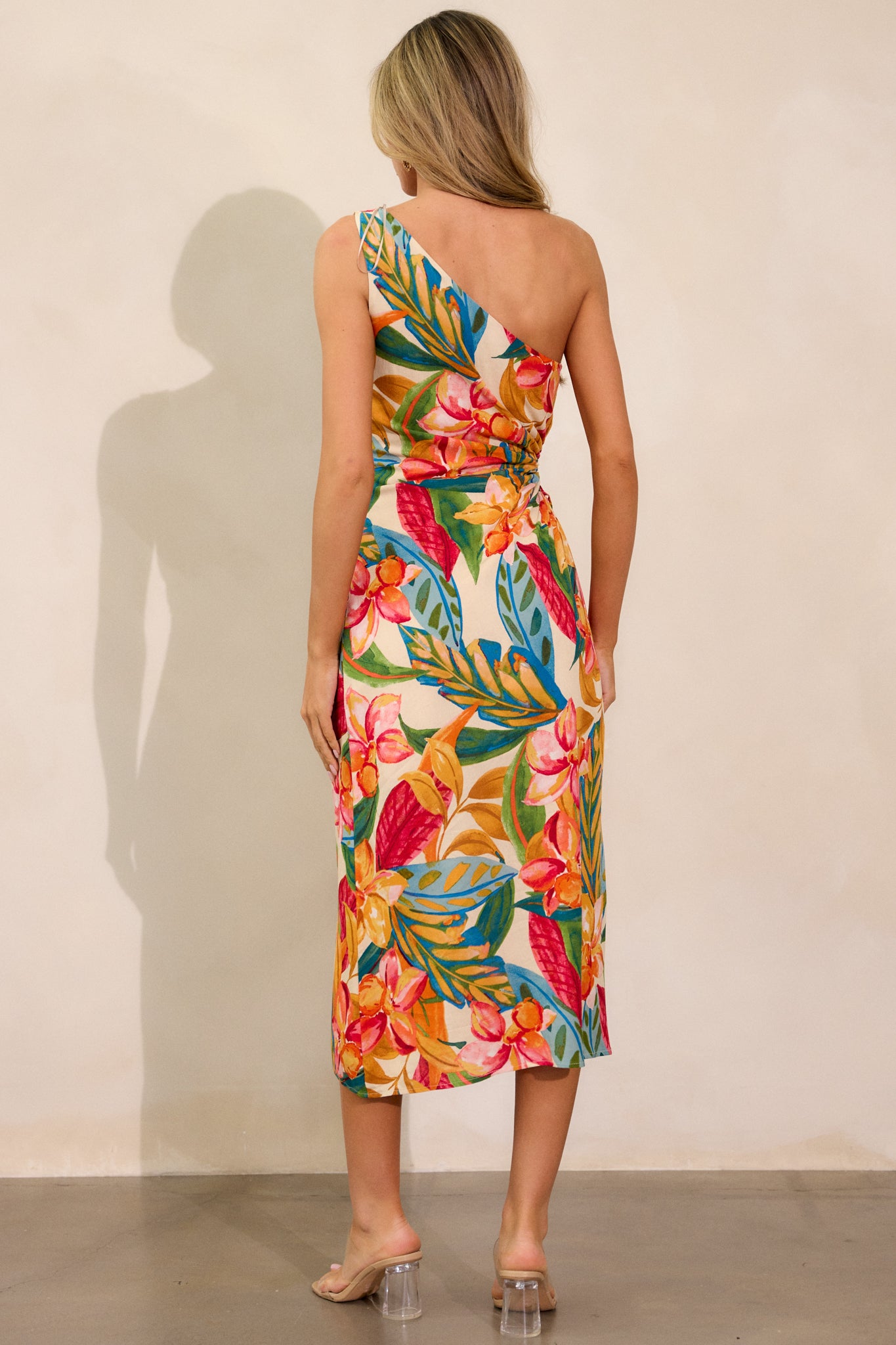 Back view of the multi-print dress, highlighting the one-shoulder design, the discrete side zipper, and the flowing silhouette of the dress.