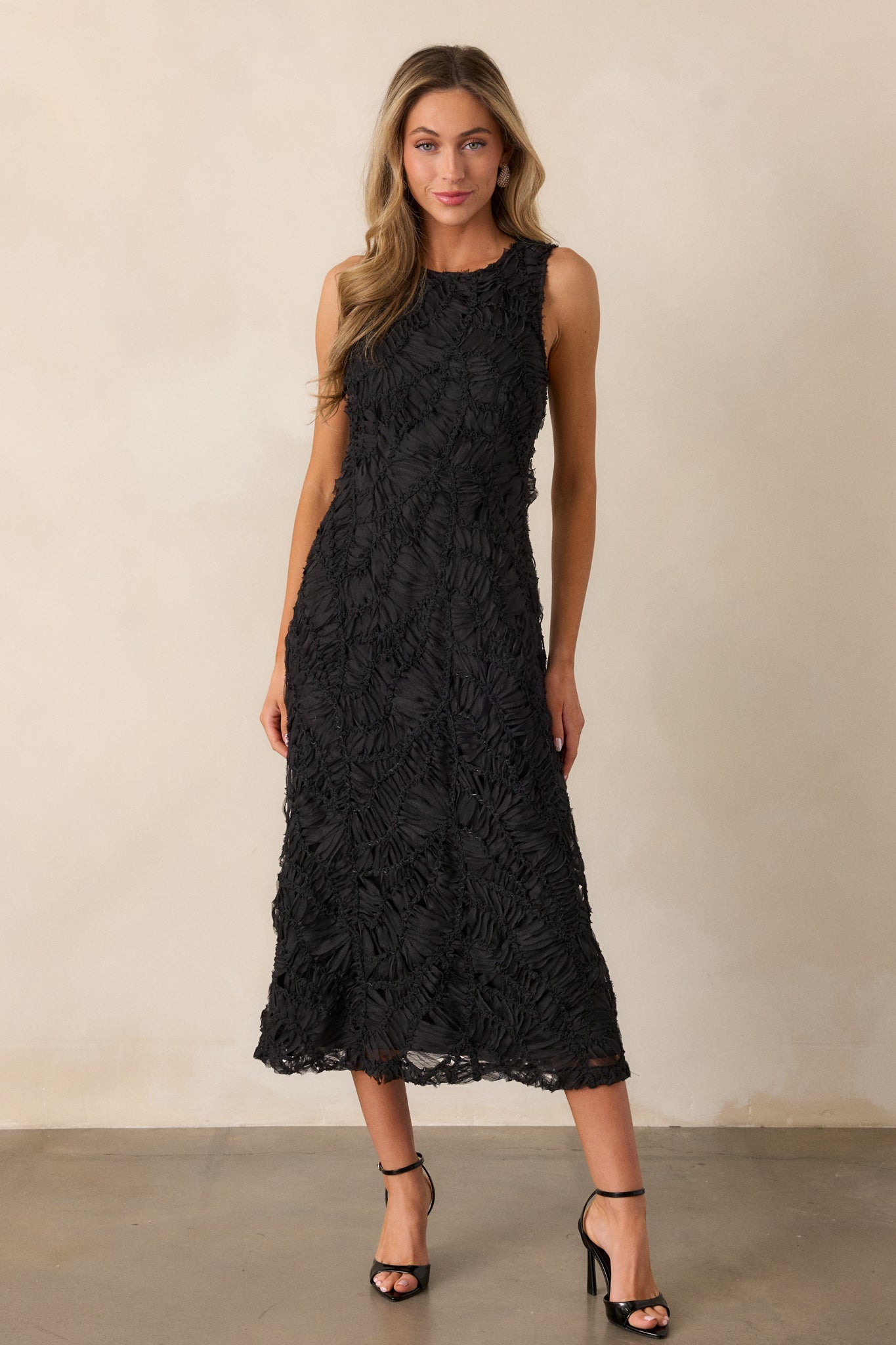 A full-body image focusing on the fit and flare shape, showing the flow of the skirt and the sleeveless design against the dress's textured fabric.