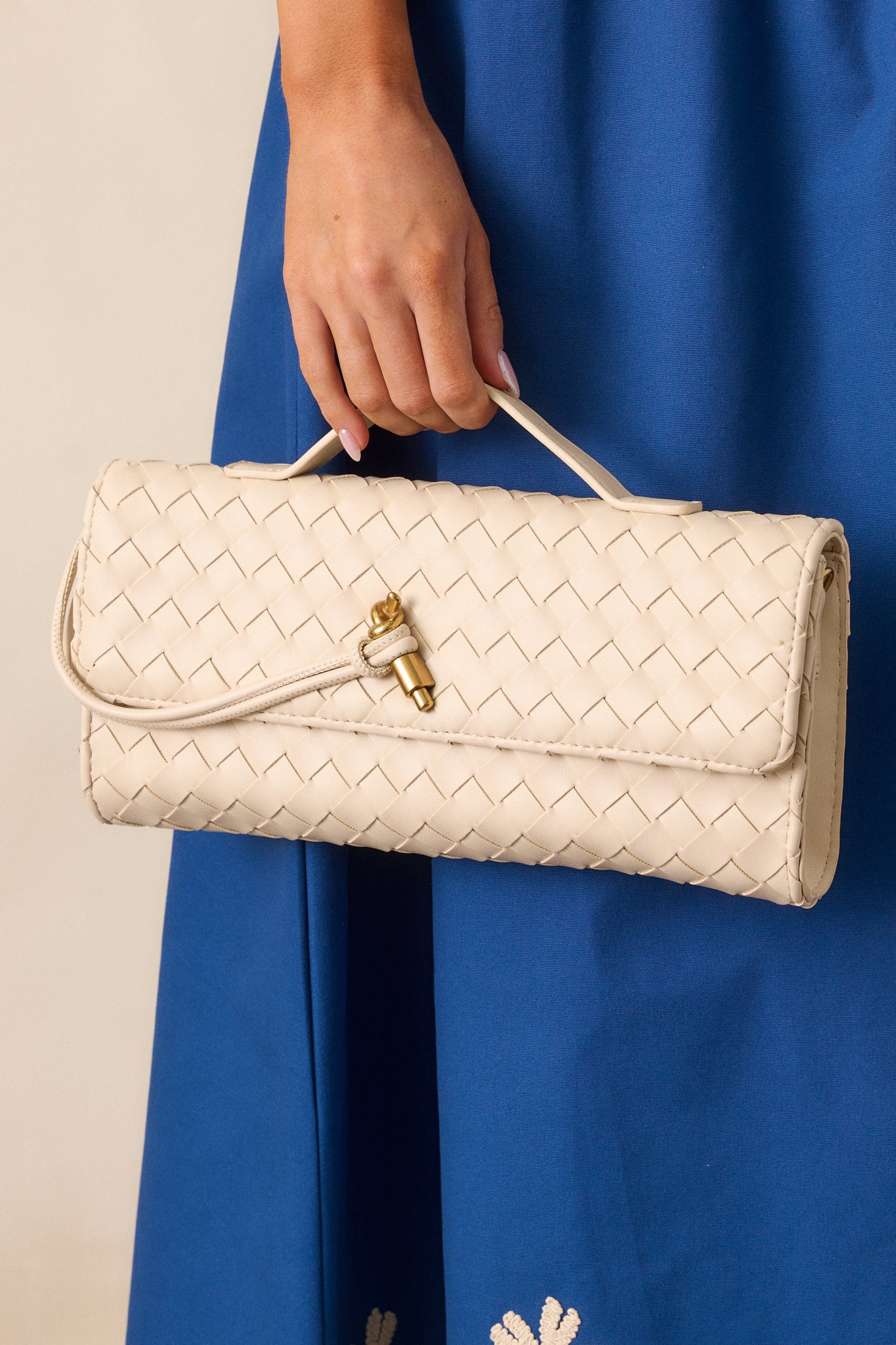 Focus on the handle and top section of the ivory handbag, emphasizing the clean lines and subtle gold accents.