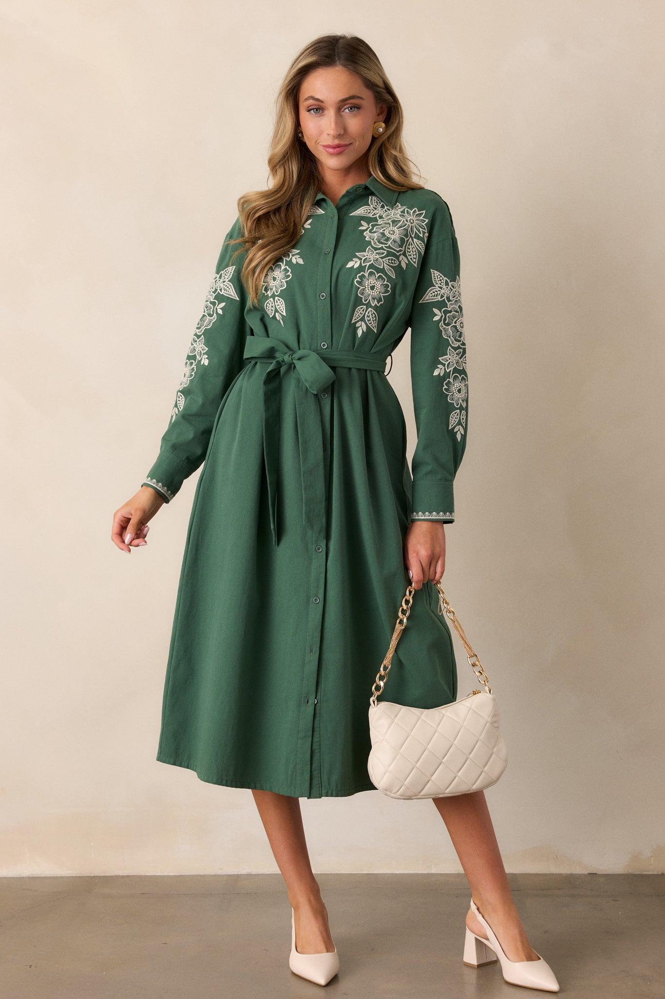 Front view of the forest green dress with a collared neckline, showcasing the intricate ivory floral embroidery on the bodice and the optional self-tie belt at the waist.