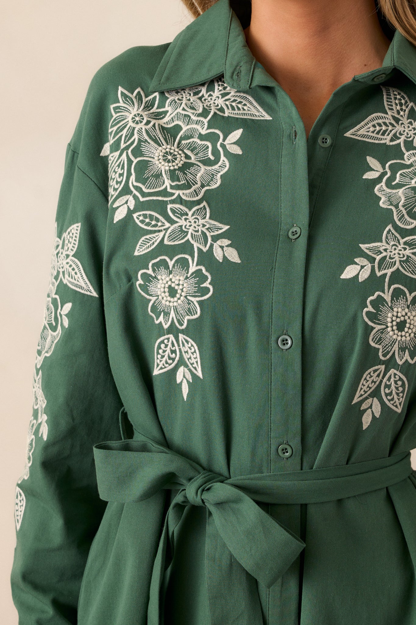 Close-up of the ivory floral embroidery on the bodice and collar, focusing on the detailed pattern and texture of the fabric.