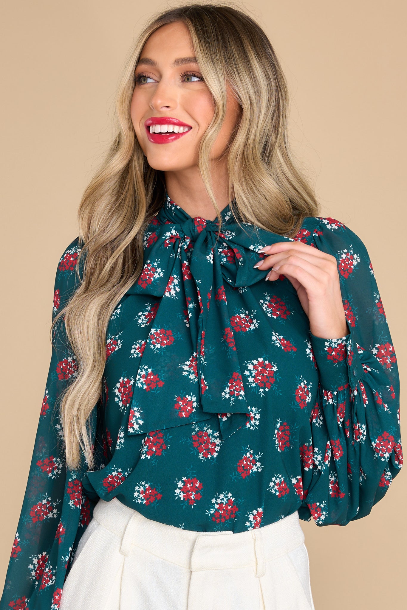 This emerald blouse features a high v-neckline, keyhole opening in the front, balloon sleeves and buttoned cuffs.