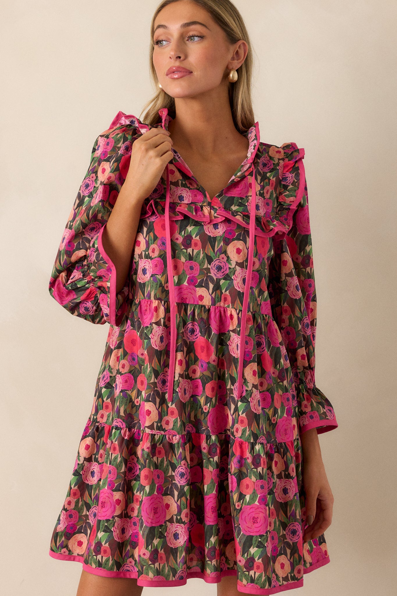 Cropped image focusing on the ruffled collar with a tie accent and the floral design on the pink mini dress.