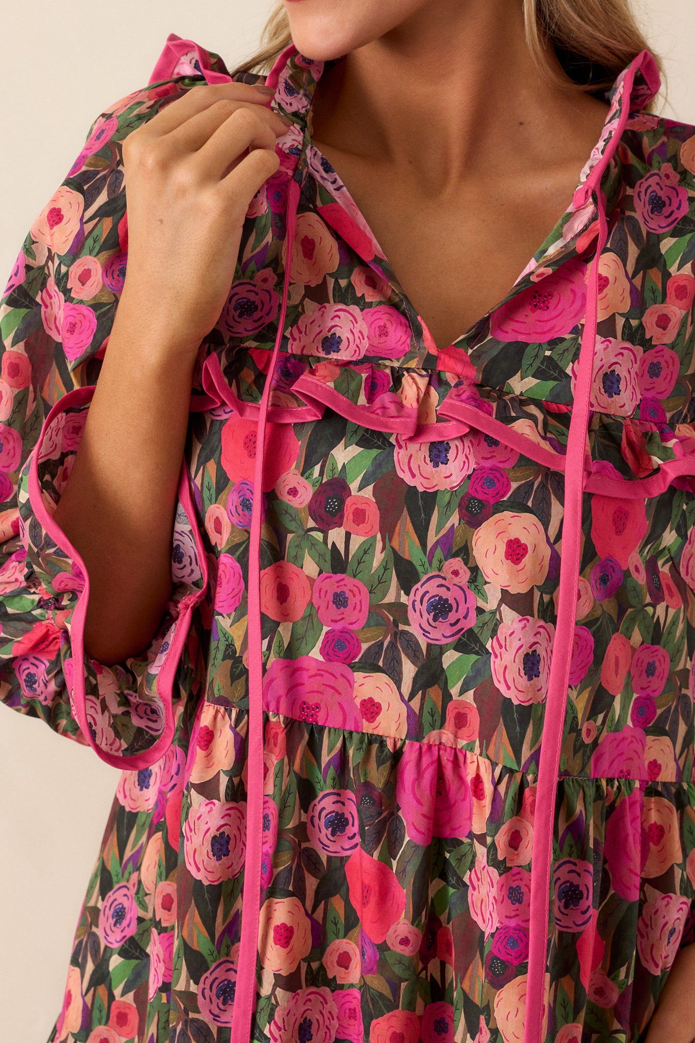 Detailed close-up highlighting the ruffle cuff detailing on the long sleeves and the intricate floral print.