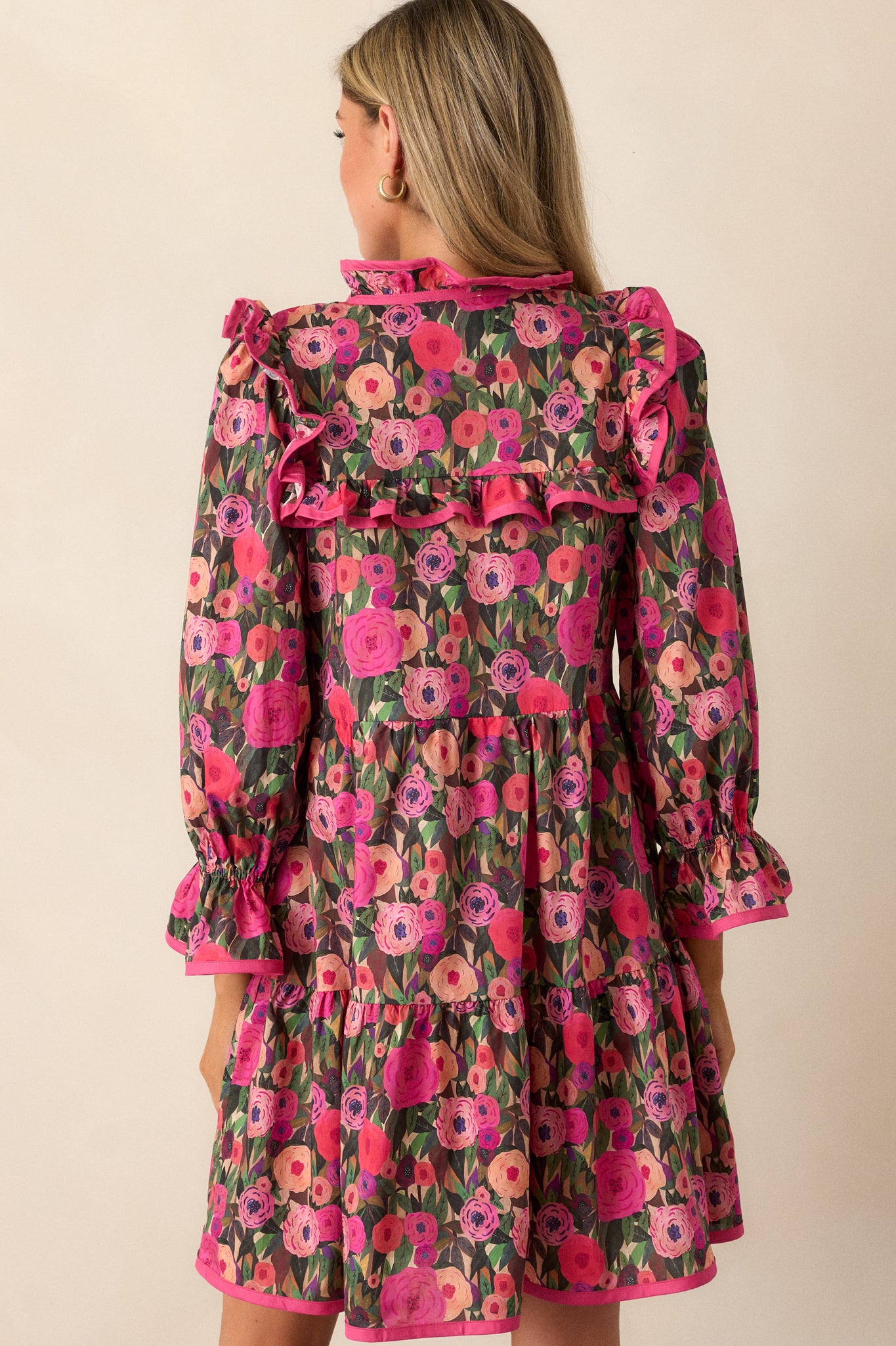 Back view of the pink mini dress showing the a-line cut, floral pattern, and ruffle accents.