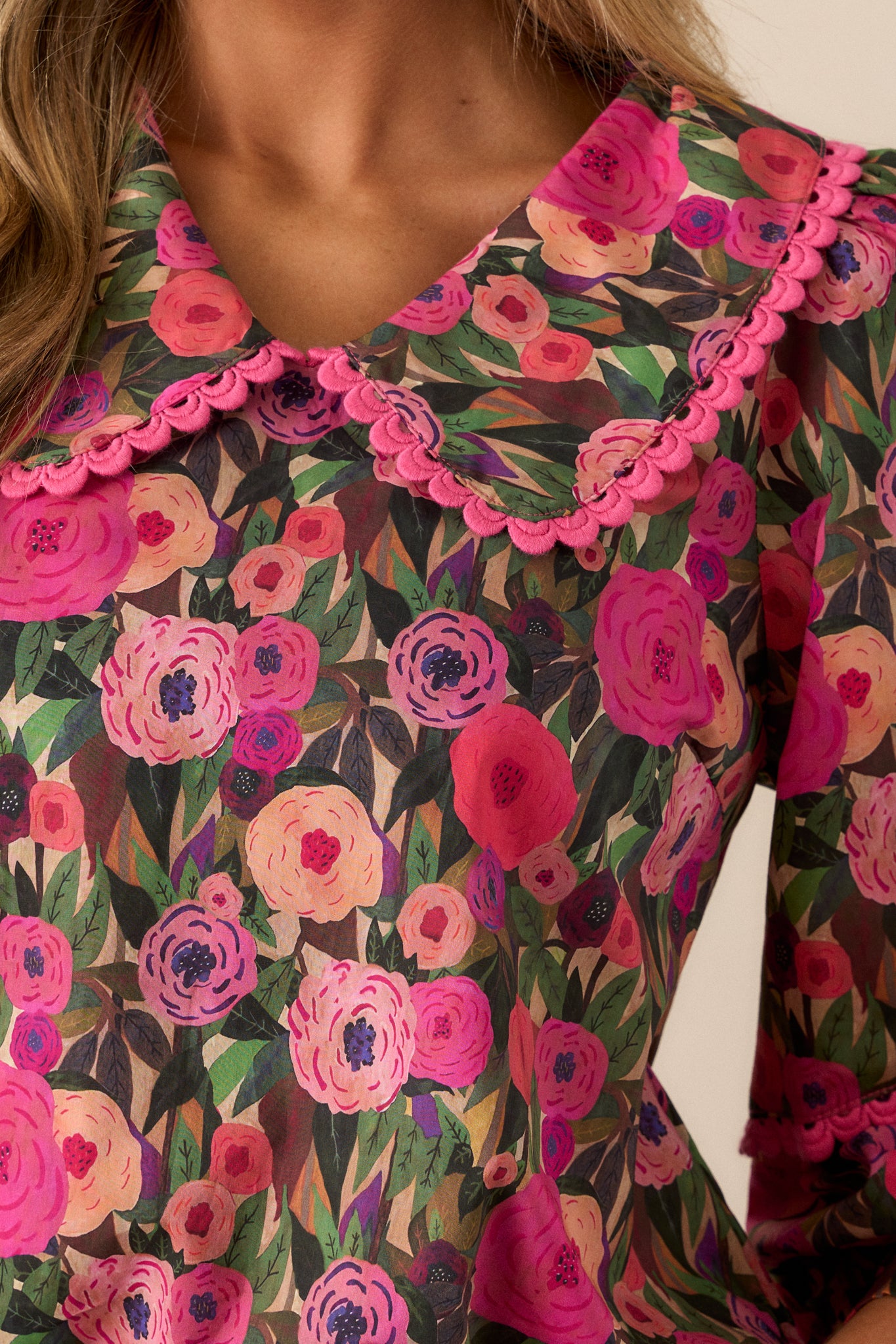 Detailed close-up of the pink scalloped trim on the collar and sleeves with the floral print on the pink blouse.