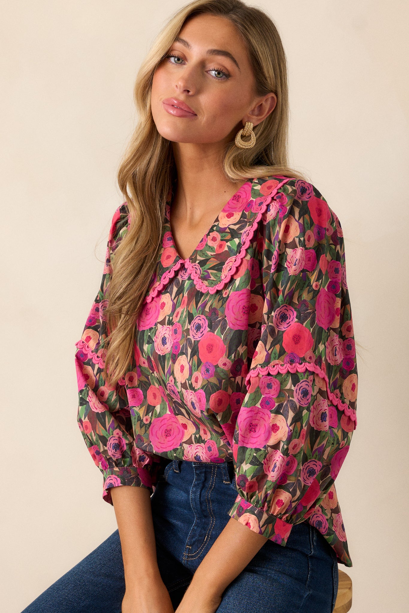 Cropped image focusing on the peter pan collar with pink scalloped trim and the floral design of the pink blouse.