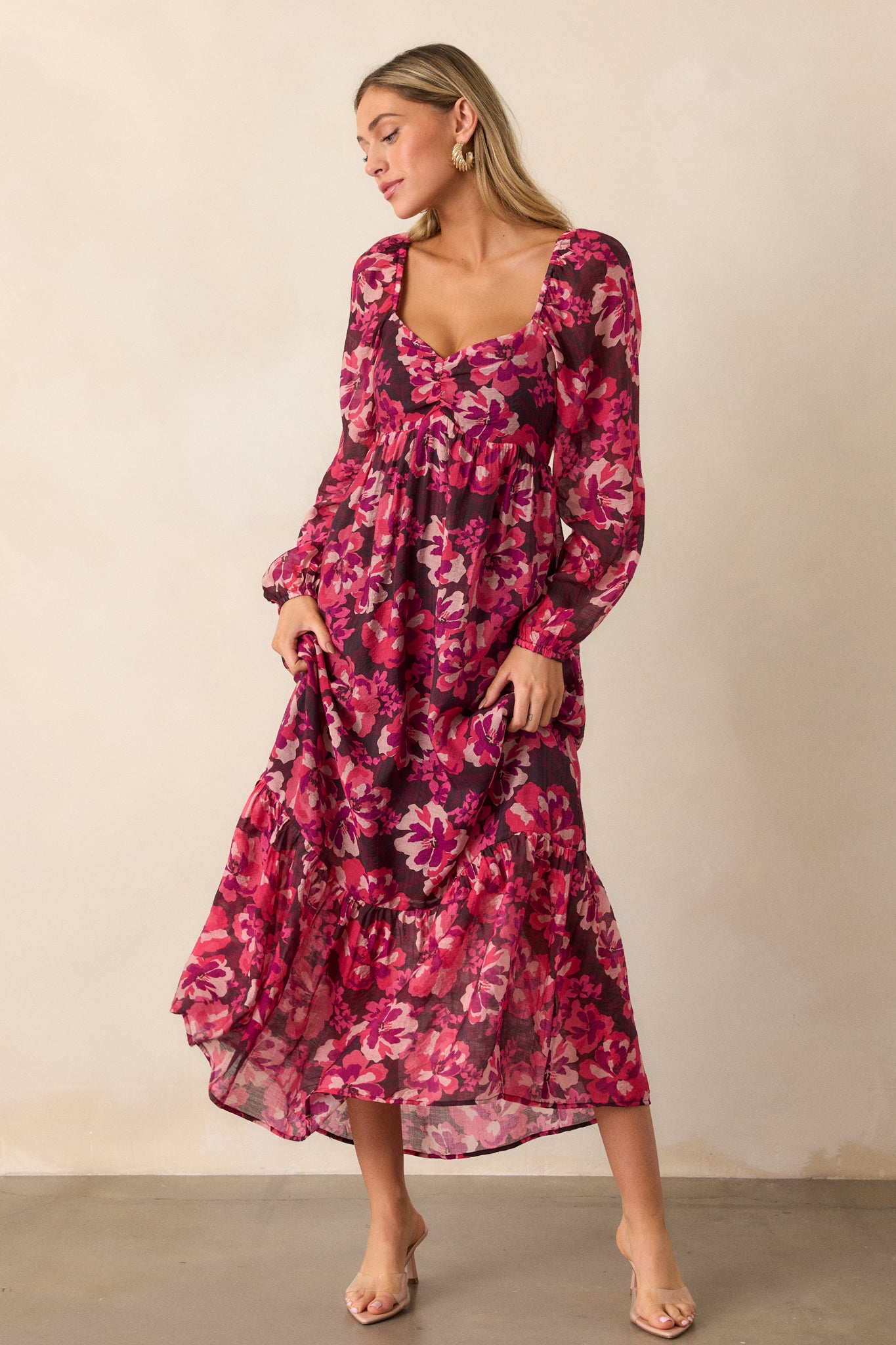 The pink midi dress displayed in full view, highlighting the ruching detail along the bodice and the elegant long sleeves with elastic cuffs.