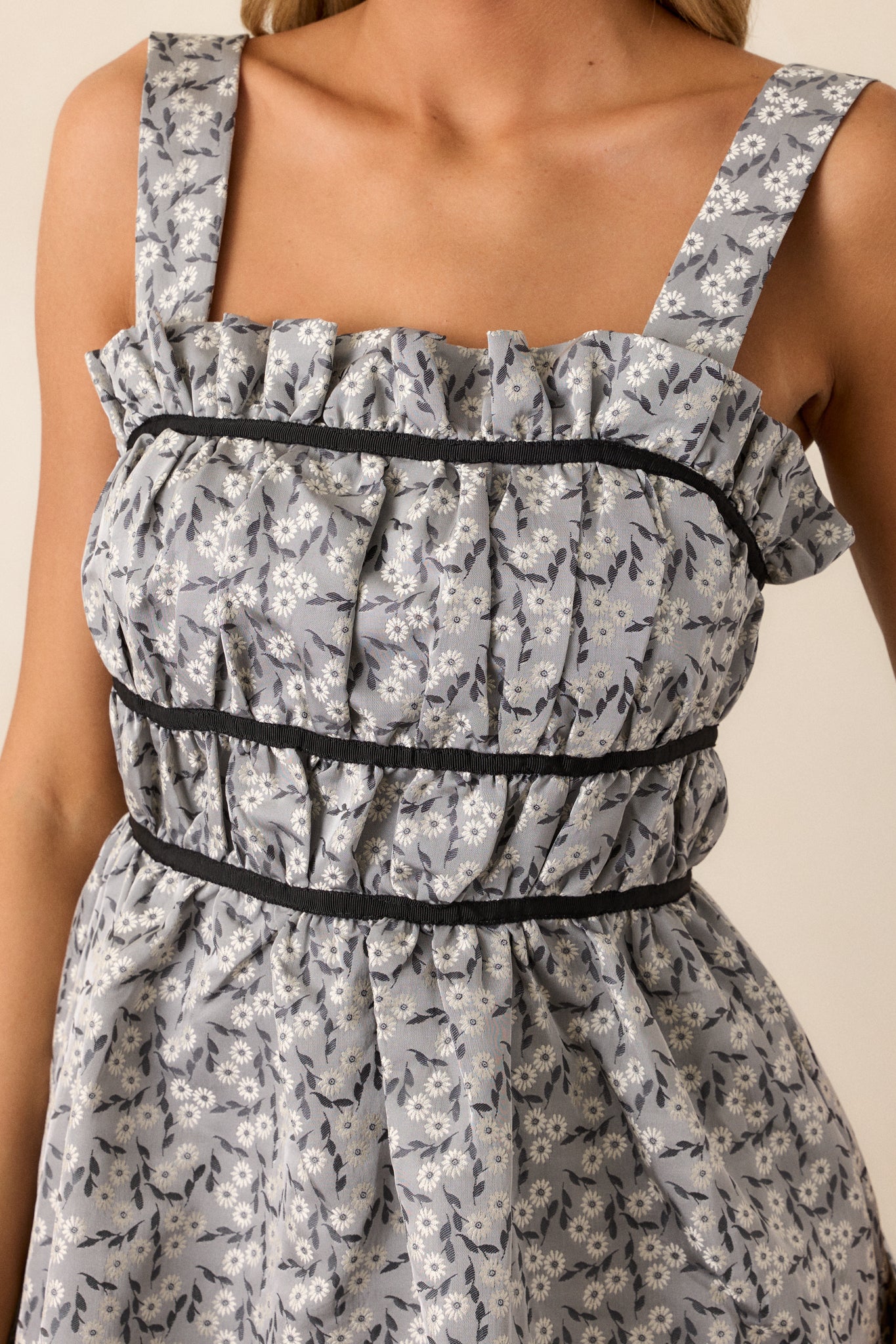 Close-up of the ruched square neckline on the grey midi dress, showcasing the texture and detailing of the black contrast trim and the self-tie bows.