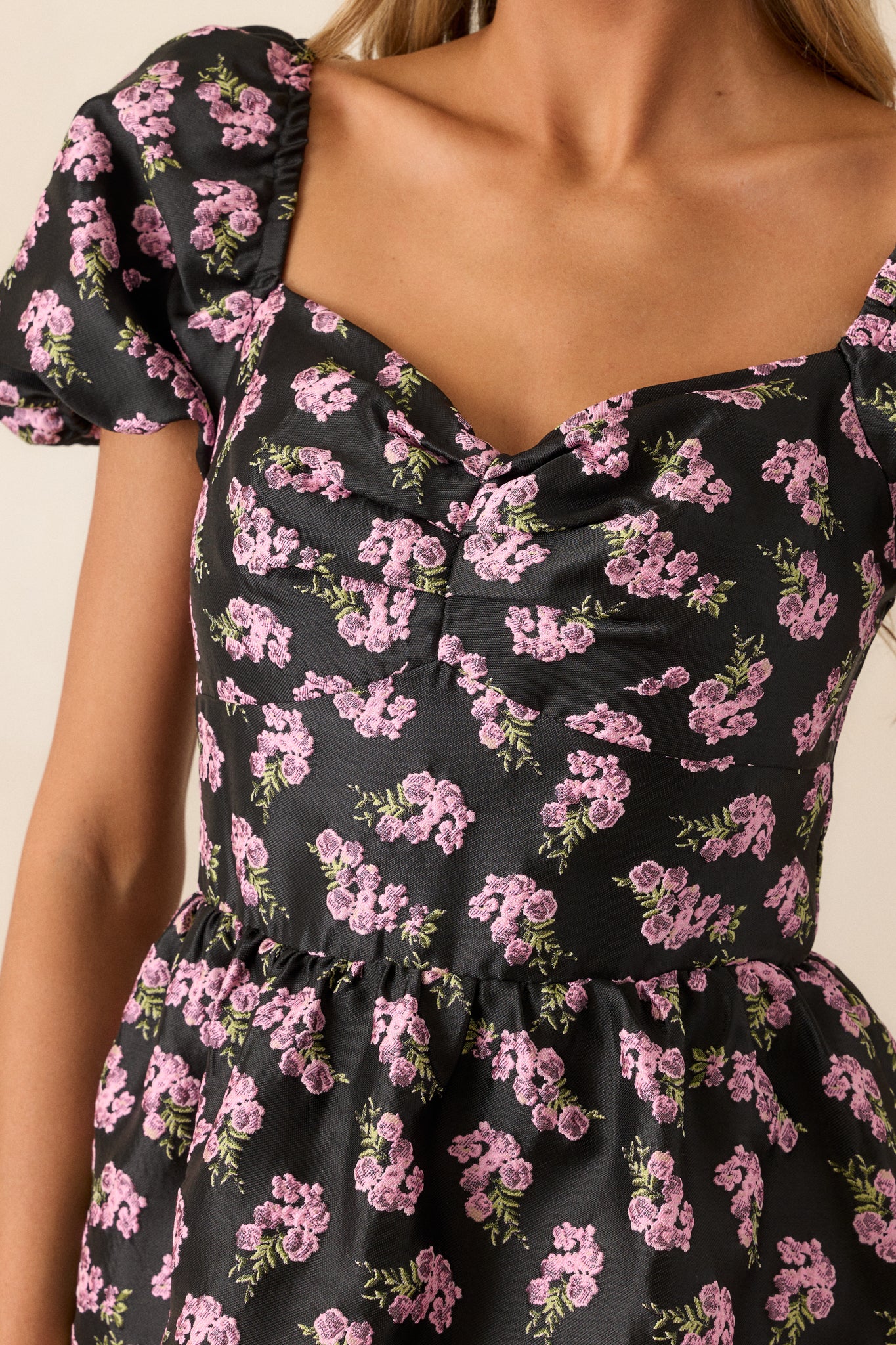 Close-up of the floral jacquard pattern on the black midi dress, showcasing the texture and vibrant colors of the pink flowers against the black background.