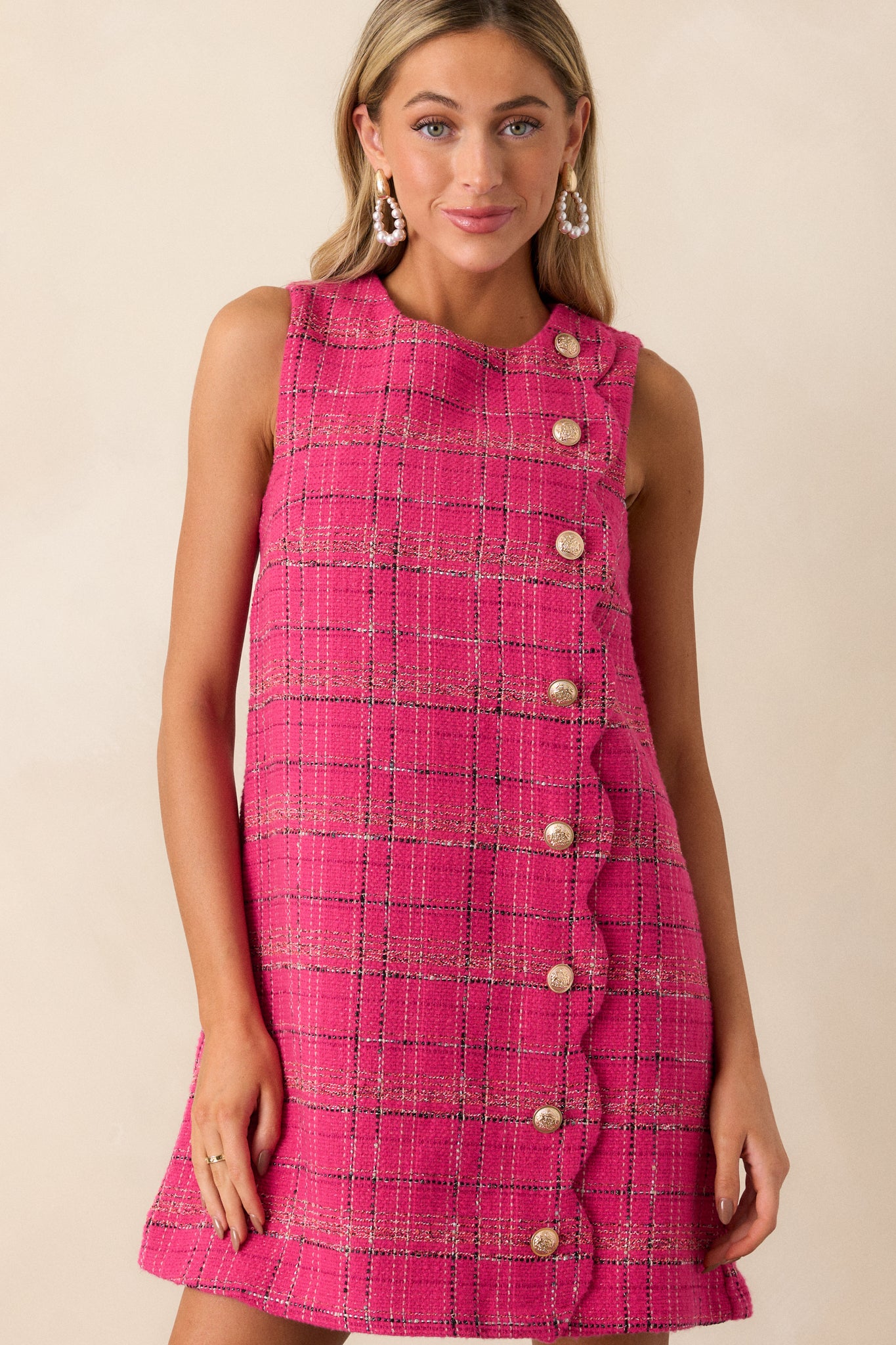 Close-up of the plaid tweed fabric of the pink dress, highlighting the intricate gold detailing and rich texture.