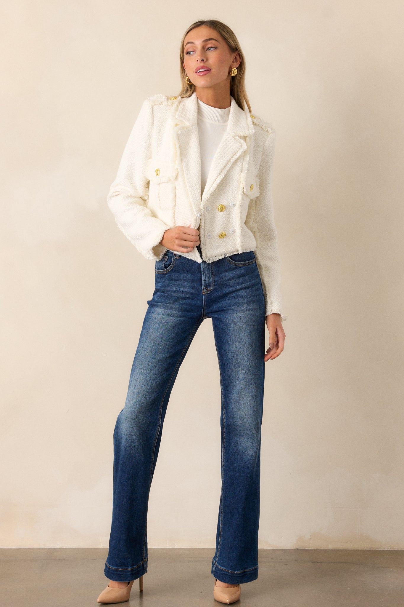 Full-length view of the white cropped blazer, showcasing the lapel collar neckline, functional button front, and raw hem detailing at the waist.