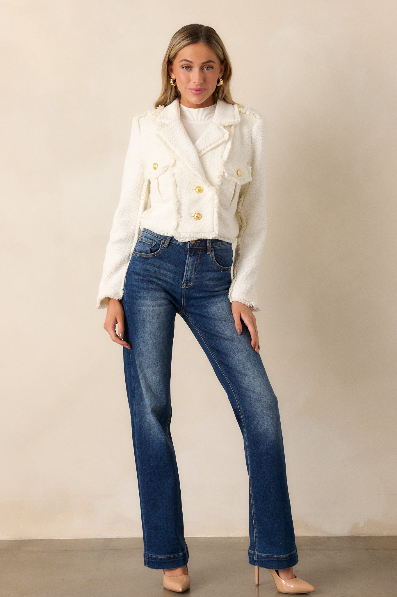 Full front view of a model wearing dark wash jeans, emphasizing the high waisted design, faded thighs and knees, and the straight leg fit.